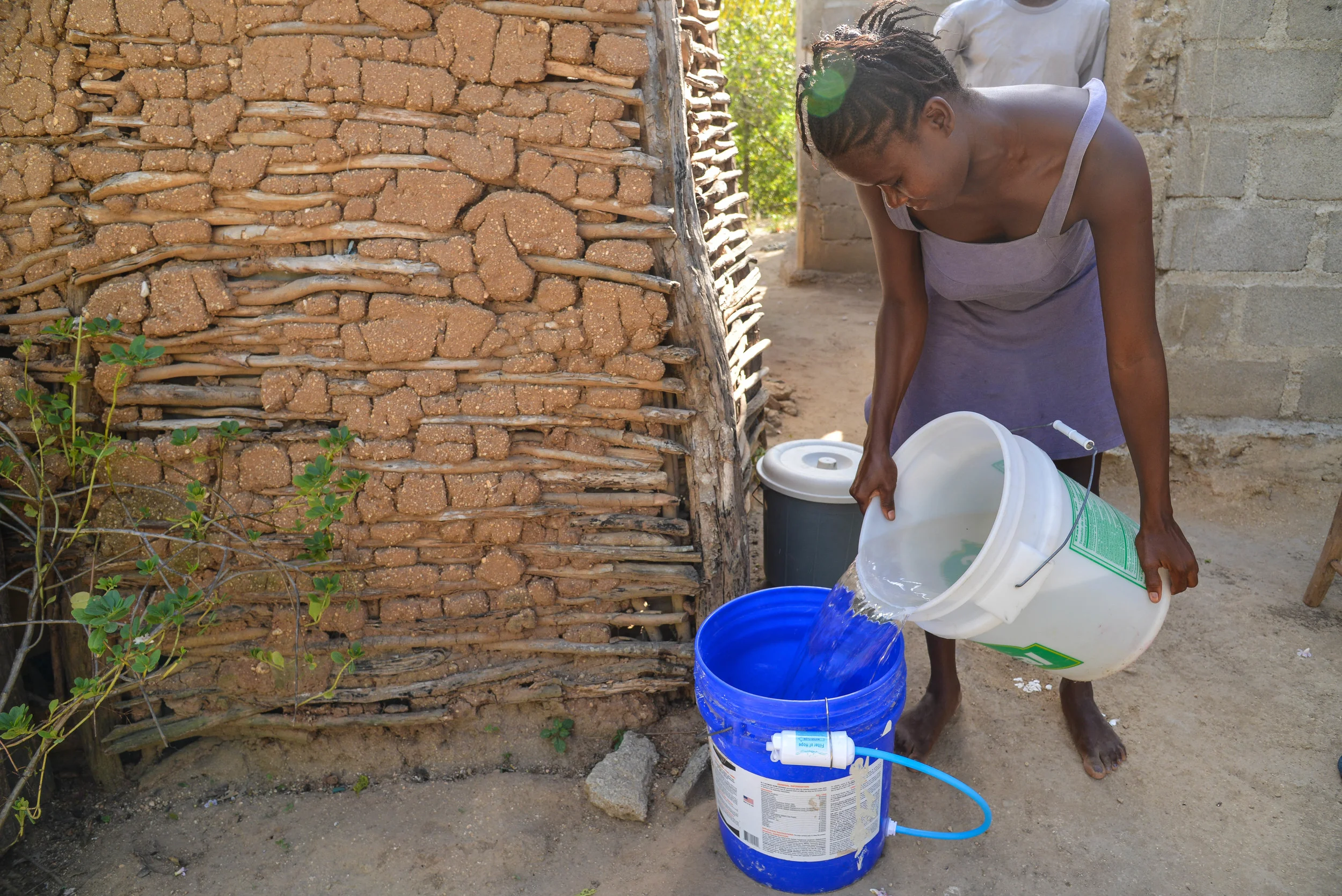 Julianise pouring water from the river into the bucket to be filtered. 