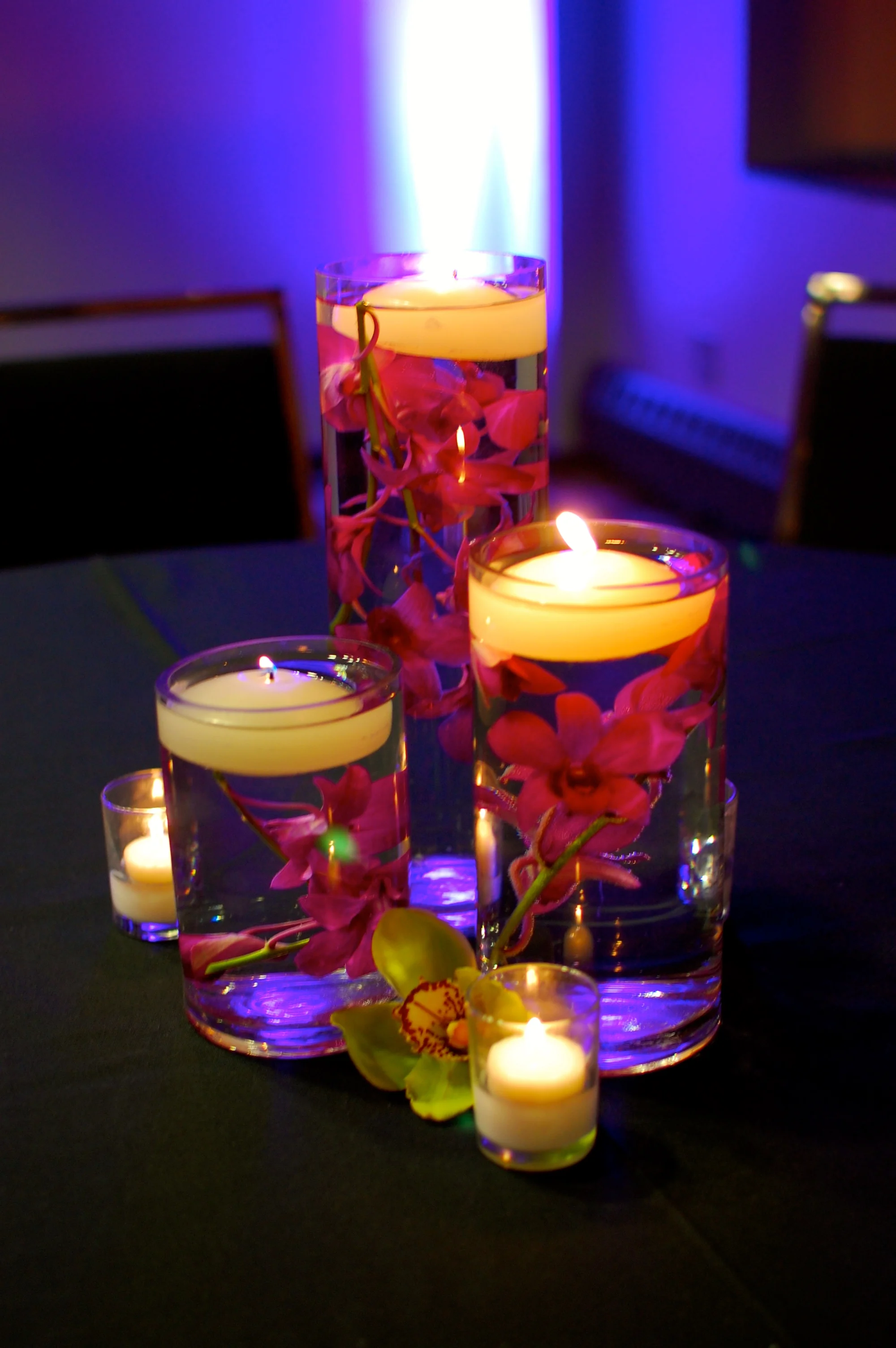 Floating candles in vases filled with purple orchids give the tables a simple and elegant look