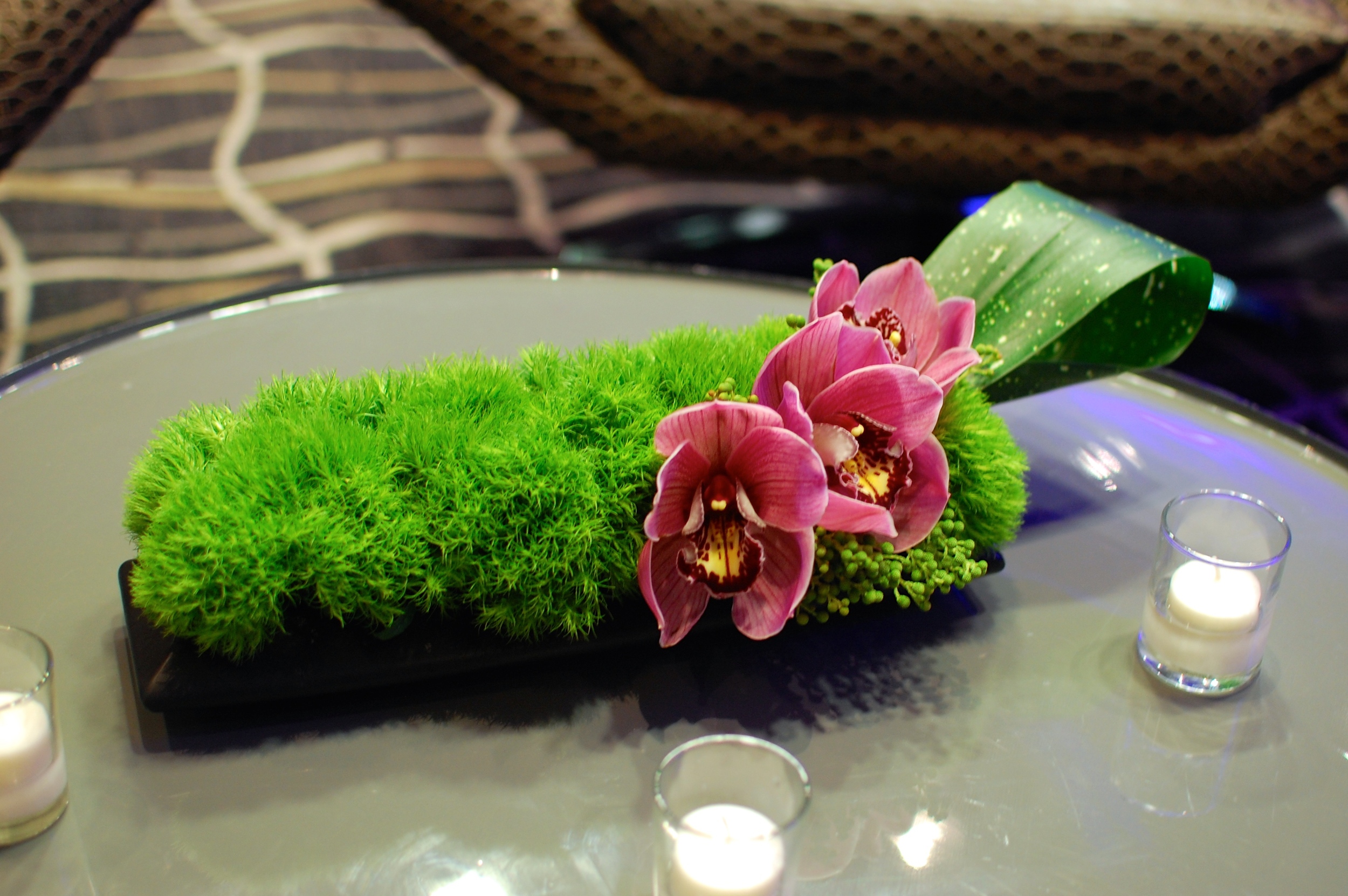 Long arrangement of green dianthus and cymbidium orchids dressed up the coffee table
