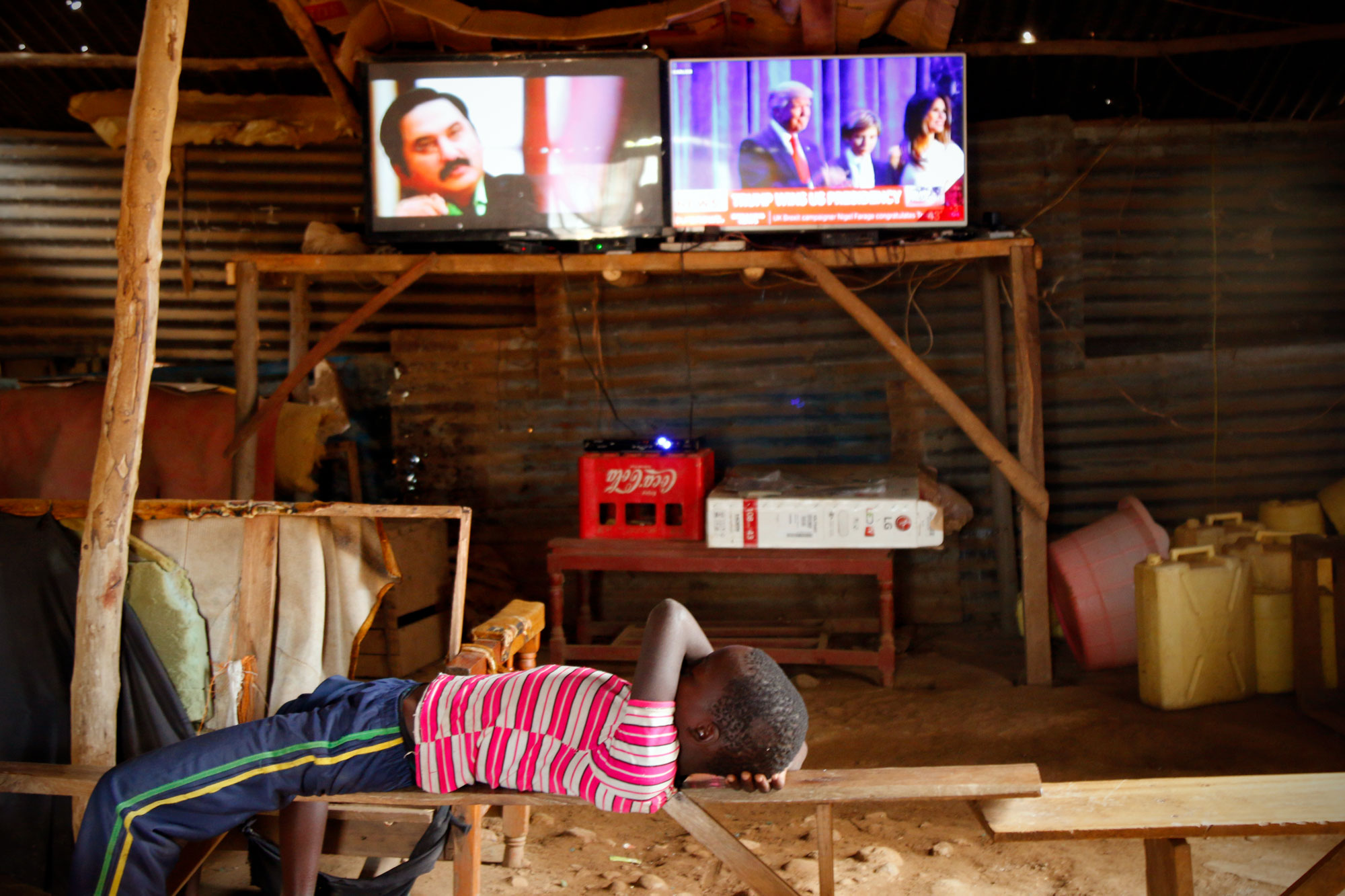 A kid naps in a “video store,” while news of Trump’s win comes in on the TV, courtesy of solar power. (Tim McDonnell)