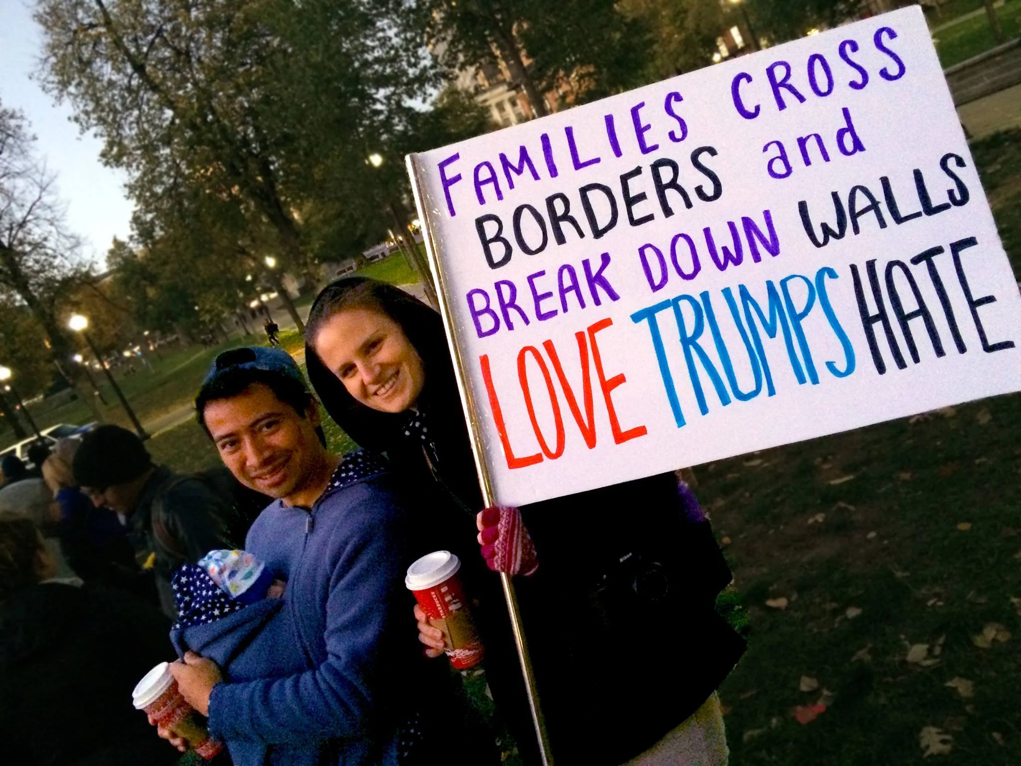 A multi-racial family at the peace rally with their newborn. "Families Cross Borders & Break Down Walls"