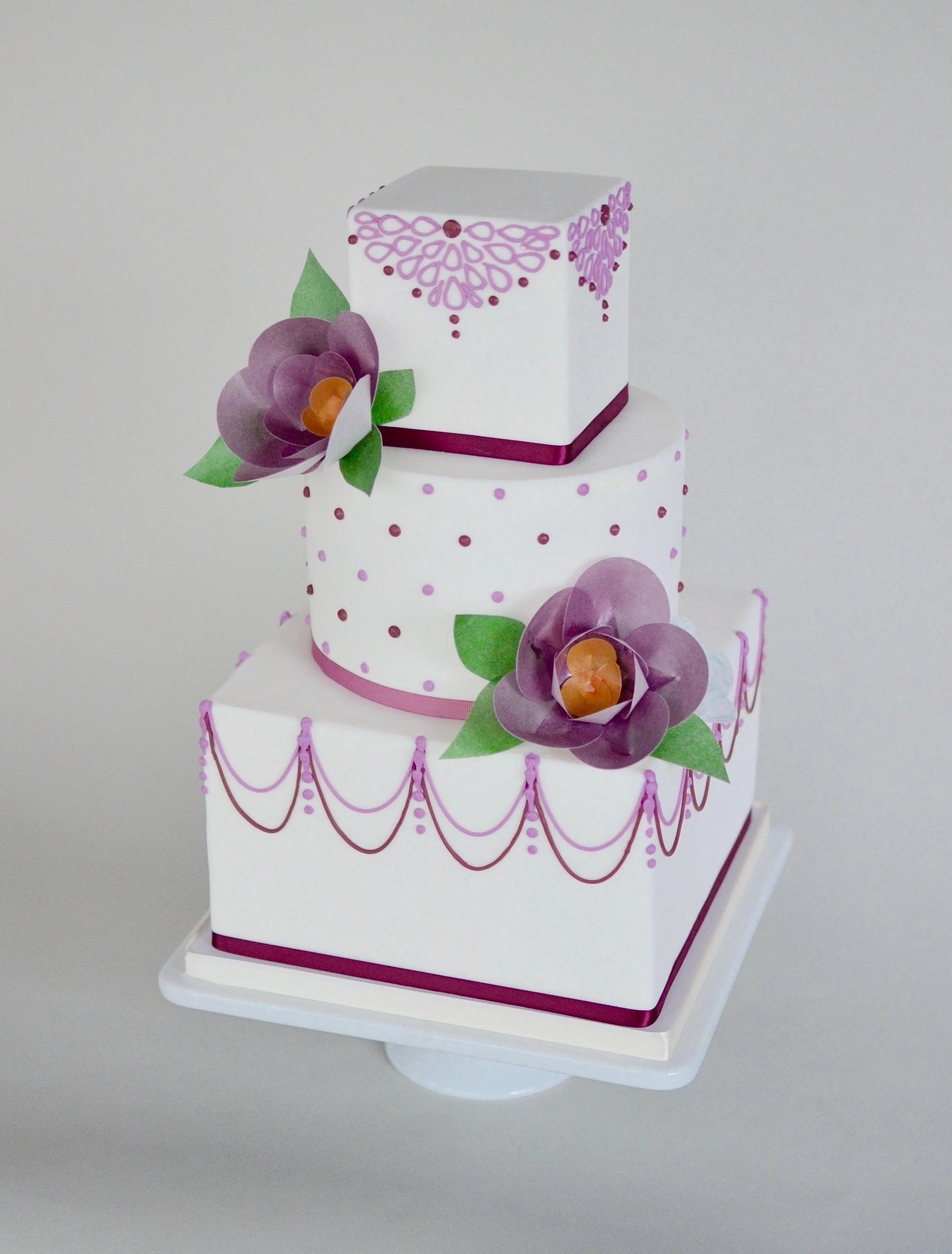Plum and lavender wedding cake with piped details and wafer-paper flowers. Image © Carla Schier.