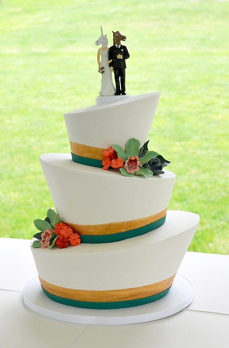 Topsy-Turvy wedding cake with teal and gold trim, and colorful sugar flowers. Image © Carla Schier