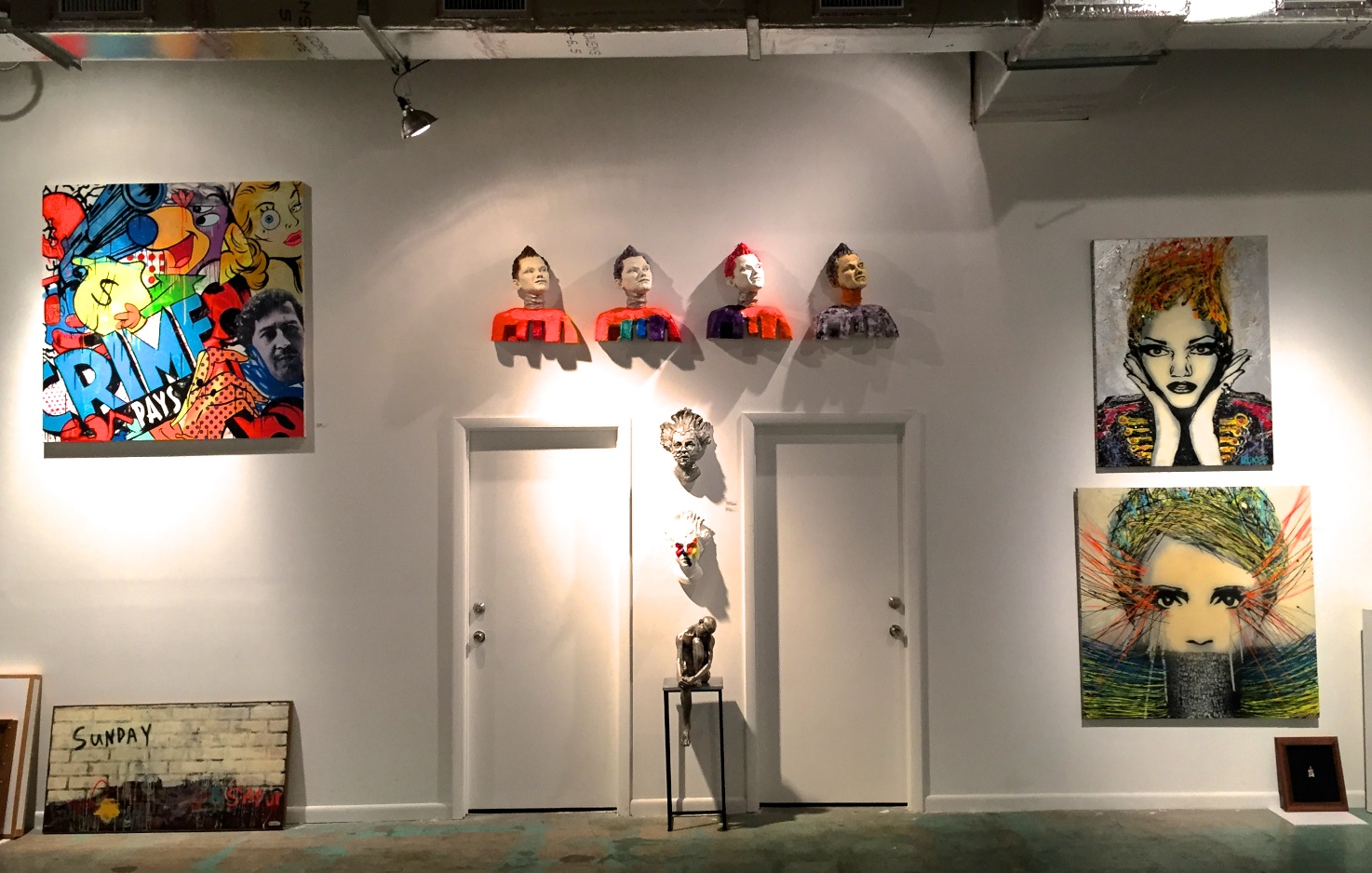 Wall-mounted head sculpture installation, contemporary figurative sculpture mask head sculpture multiples installed in Wynwood Miami at Port of Angels, a pop-up installation during Art Basel Miami 2015. Wall-art inspired works by Timmy Sneaks on left and BLikeMe on right.