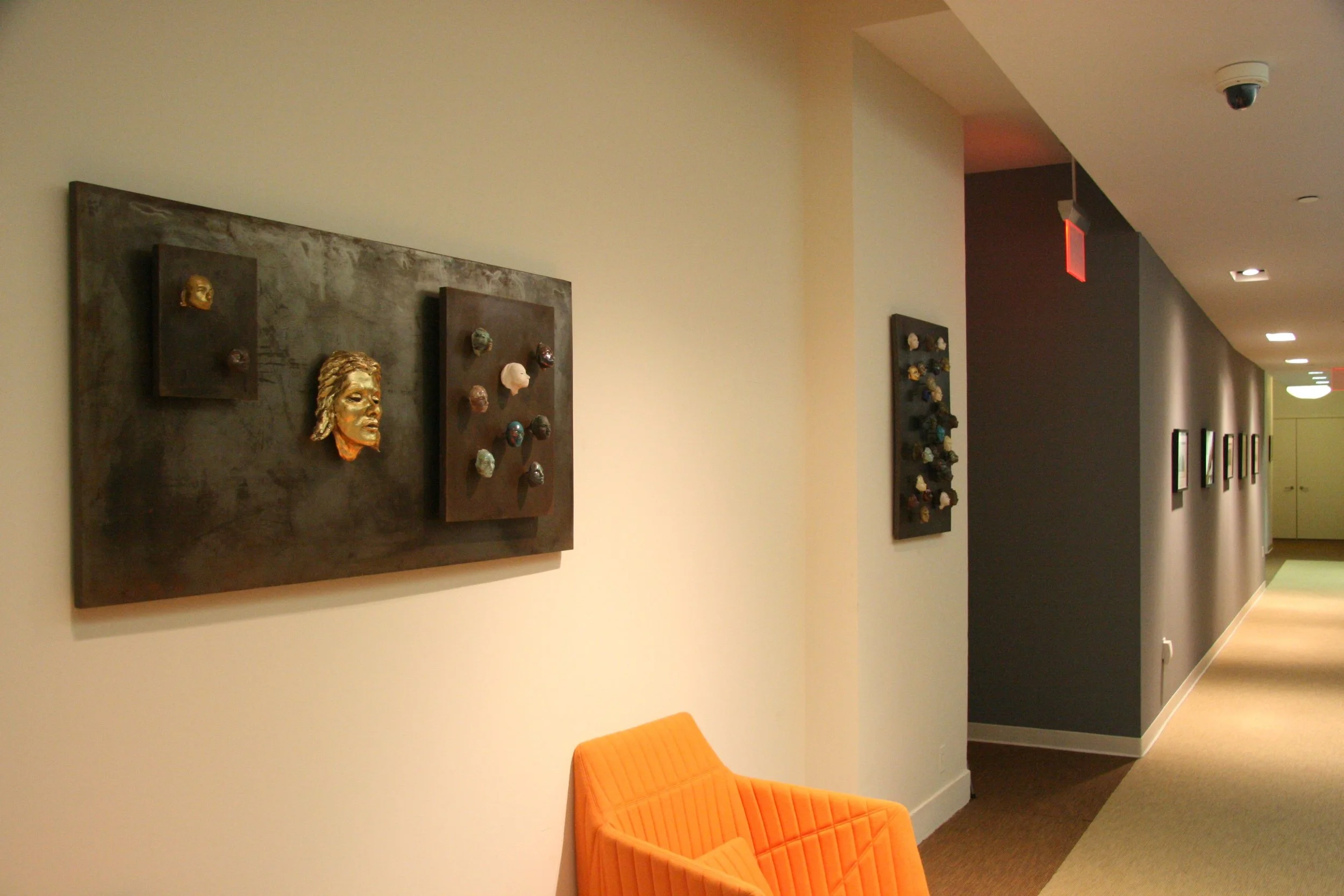  This wall relief, ceramic heads on steel plates is available, and the central gold leaf head could be replaced with something slightly larger, or another similar piece created.  27”H x 53”w 