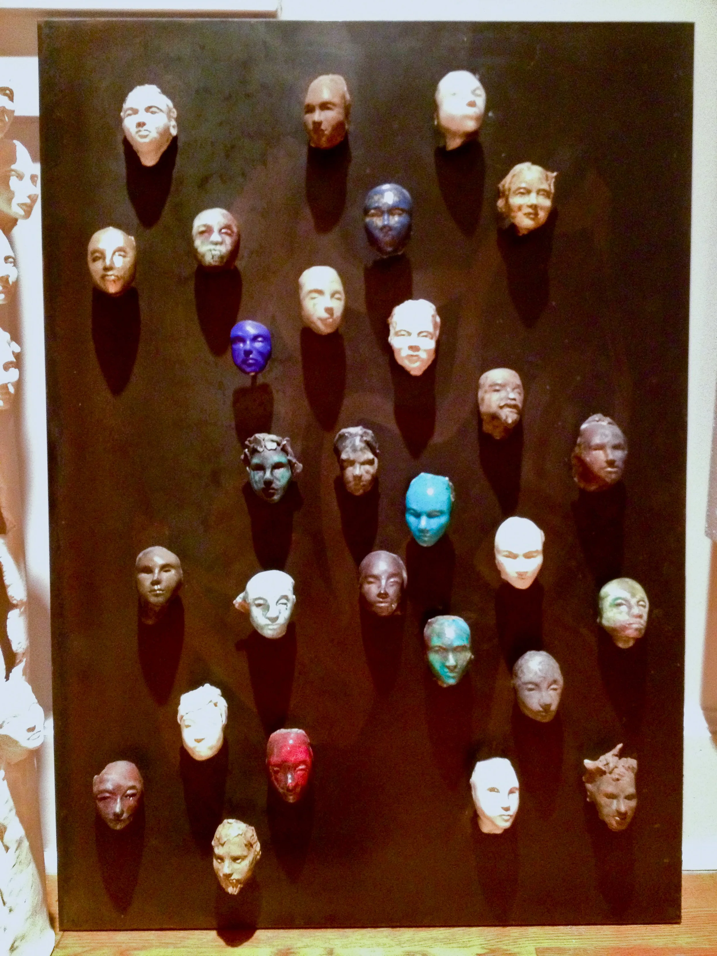  A collection of colorful glazed heads on steel wall mounted panel could be created in any size you like.  Steel is thin (16 gauge) mounted on wood to reduce weight and give a way to hang the work on a wall. 