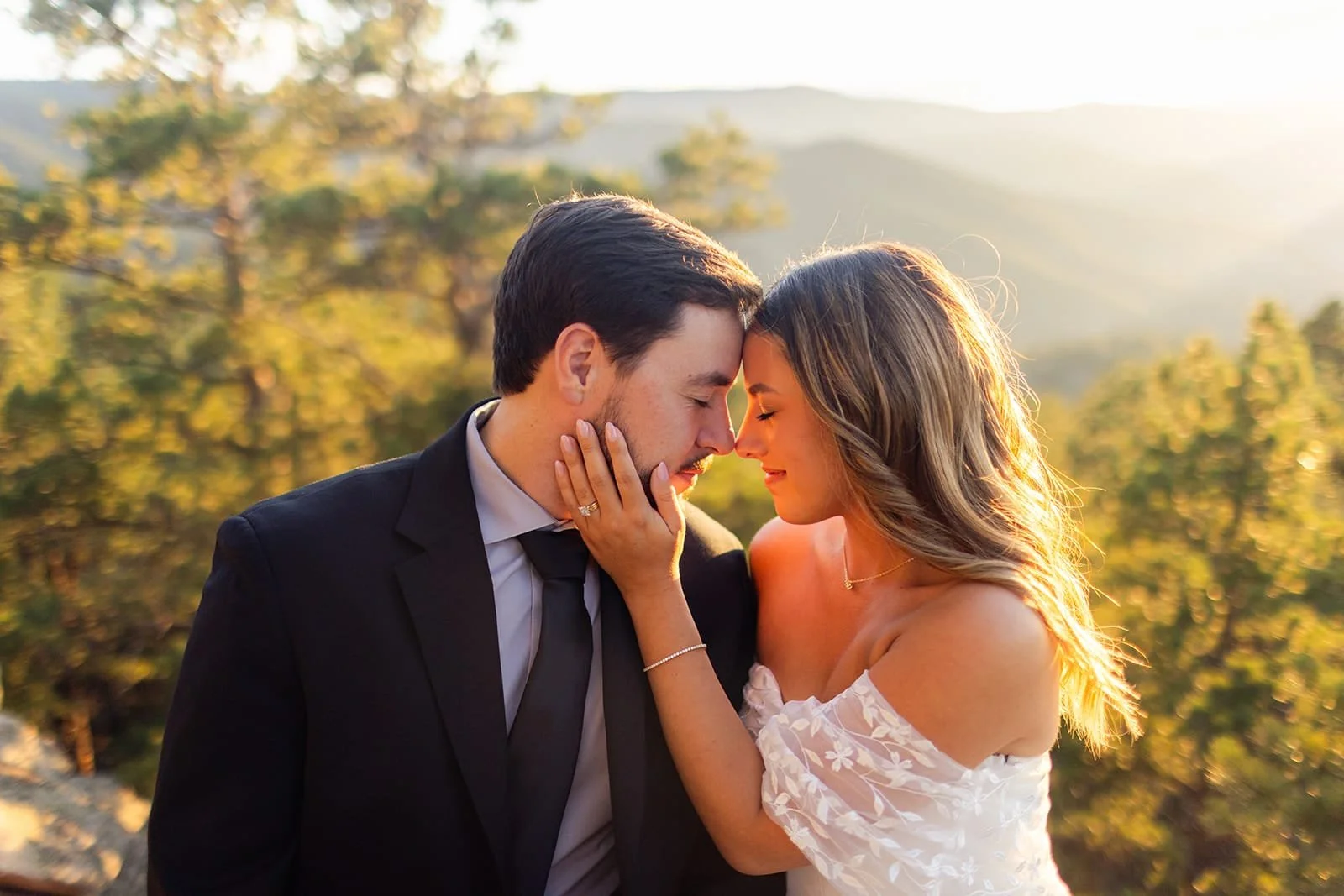 A just-married elopement couple touch foreheads with a forest background at sunset