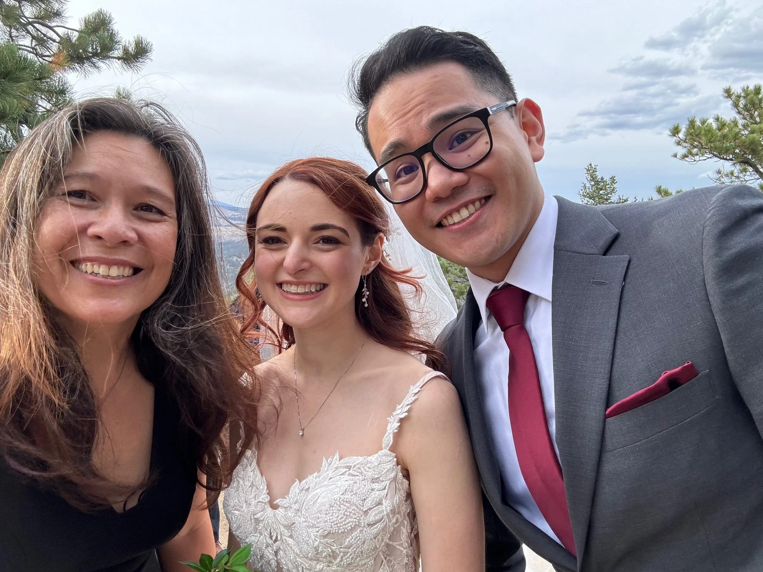 All smile while Officiant Lisa takes a selfie with Stephanie & Eddie with a forest mountain backdrop.