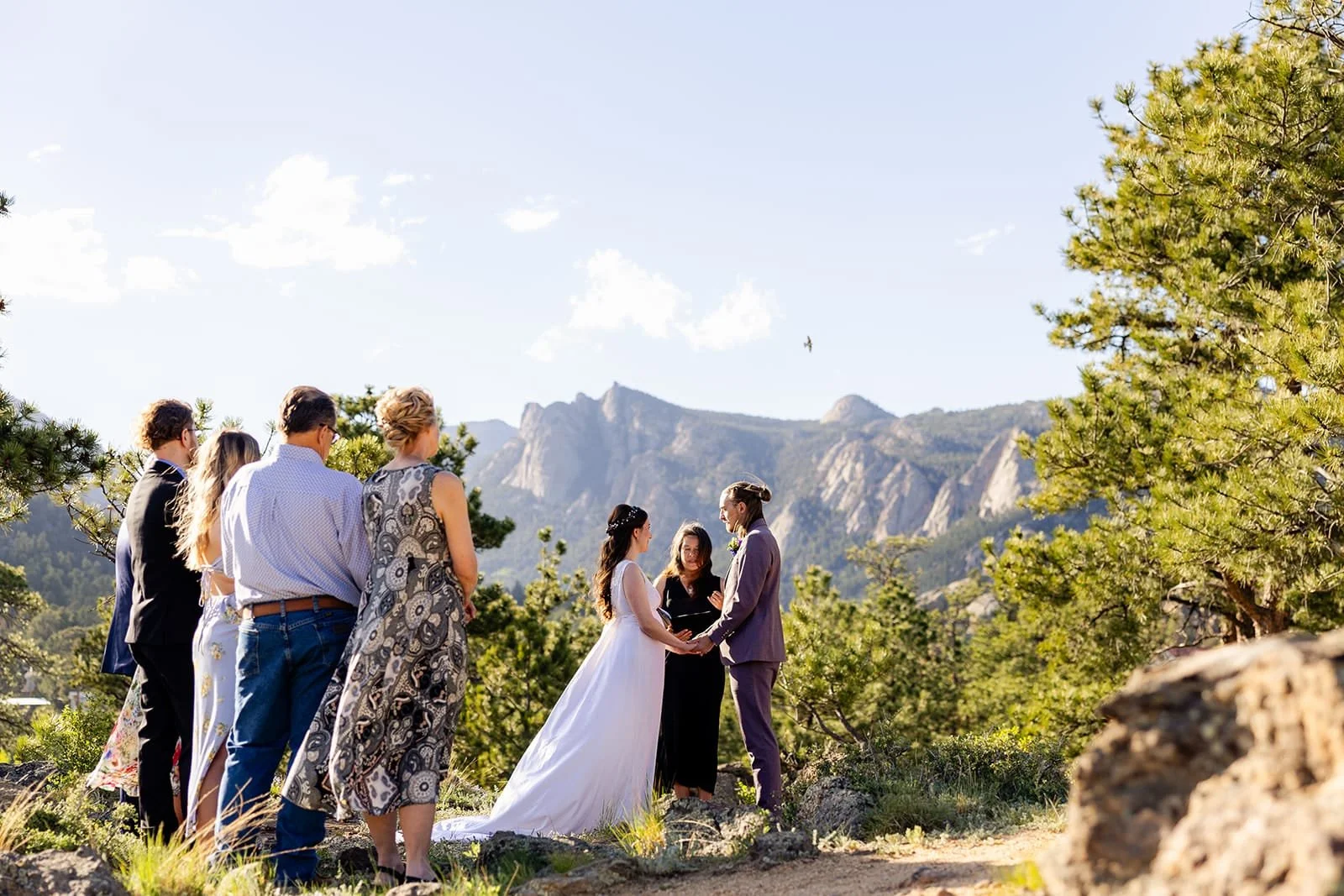 Officiant Lisa leading an elopement ceremony in a nature setting with the couple's family looking on.