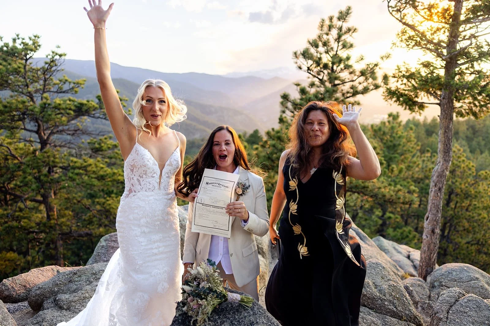 Officiant Lisa and two brides jump in celebration while they hold their marriage license