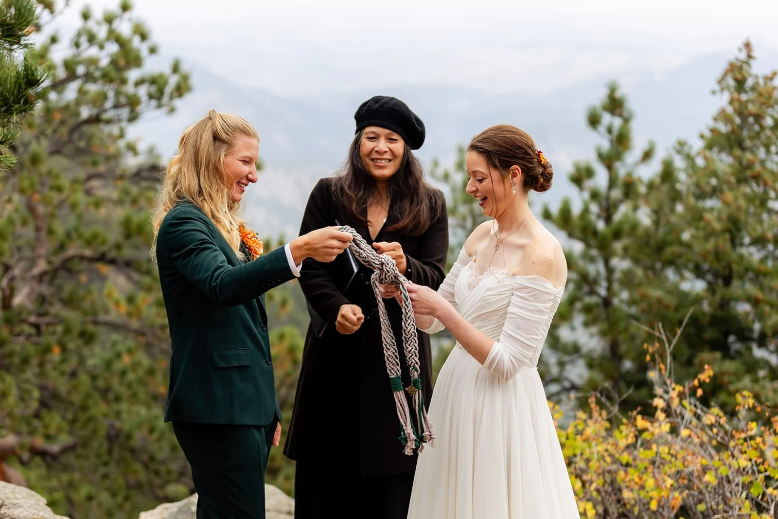 Officiant Lisa officiating an elopement ceremony with hand fasting with a green and white braided cord.