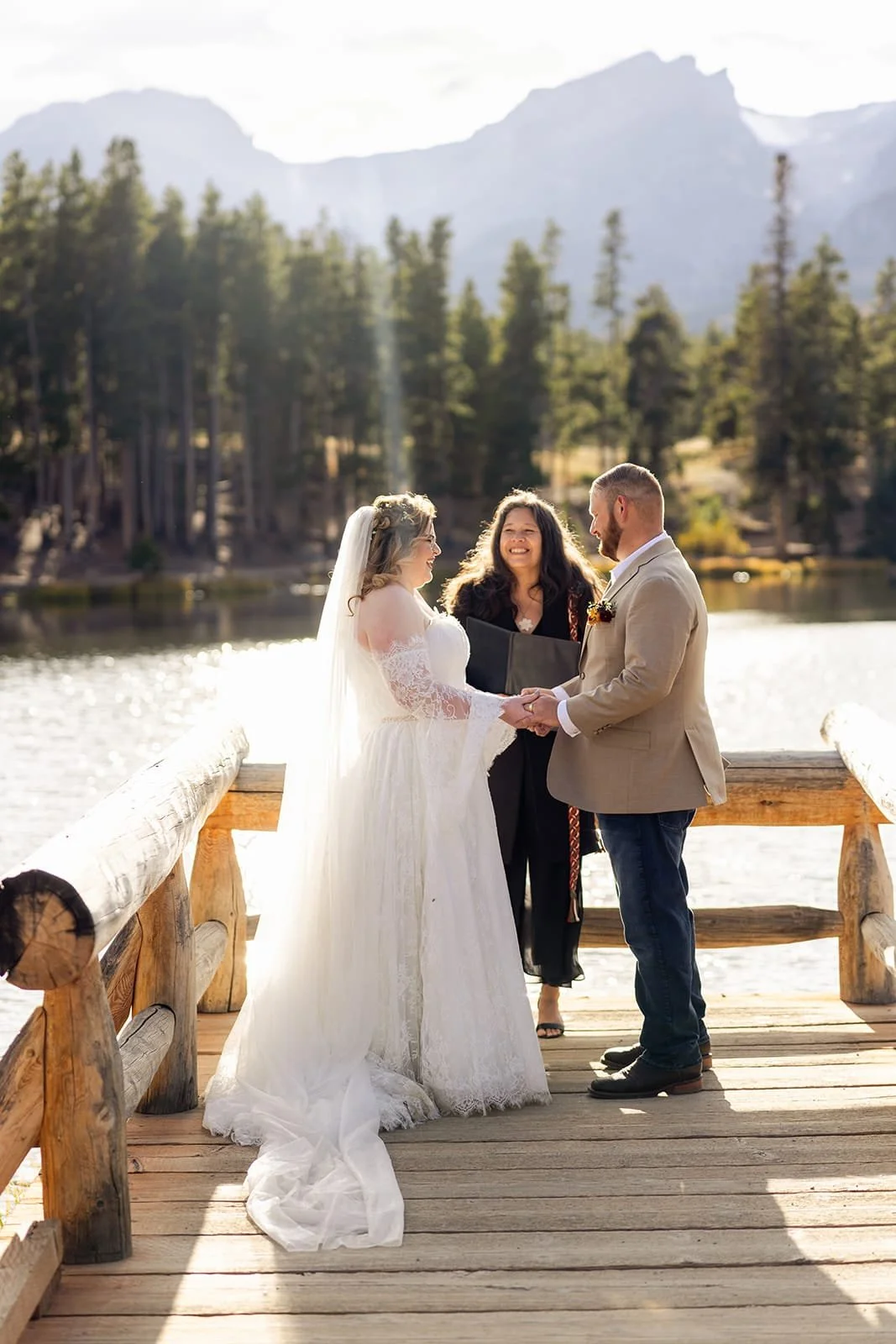 Officiant Lisa officiating an elopement ceremony on a dock next to a lake with a mountain backdrop.