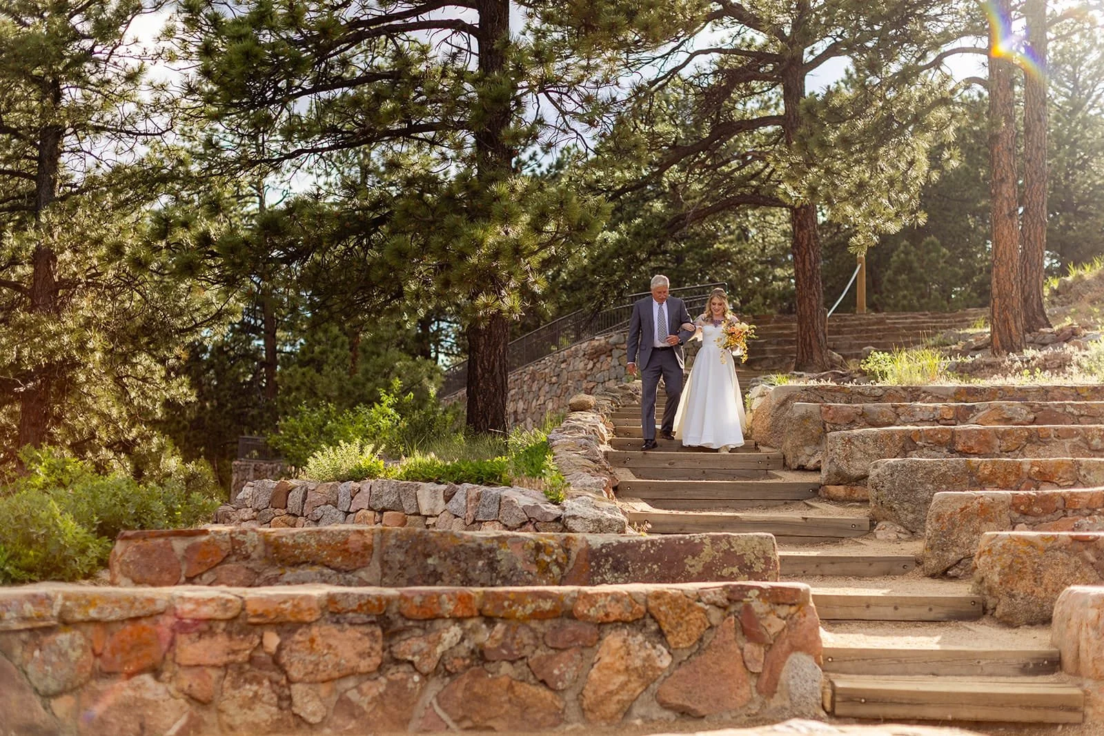 A bride walks with her father during her processional down the stairs into Sunrise Amphitheater.