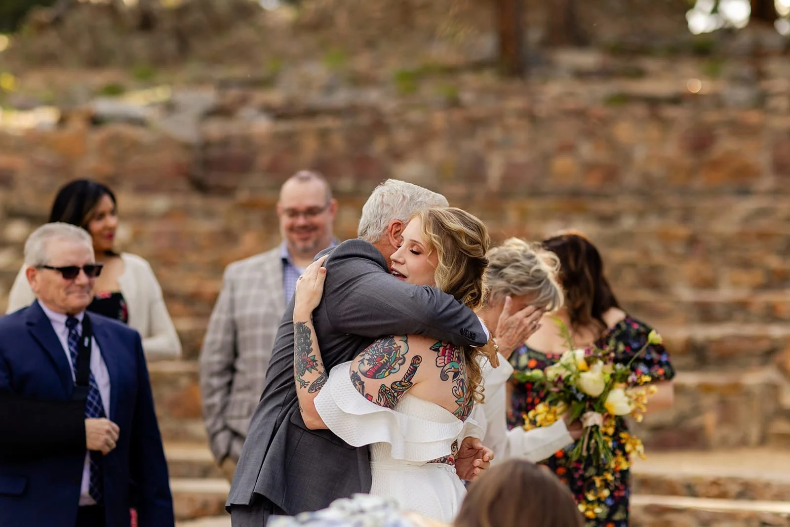 Closeup of a bride and father hugging just after her ceremony.