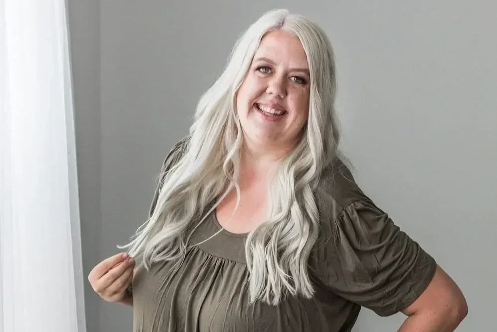 Photographer Sharee poses for a professional headshot while smiling with a grey backdrop.