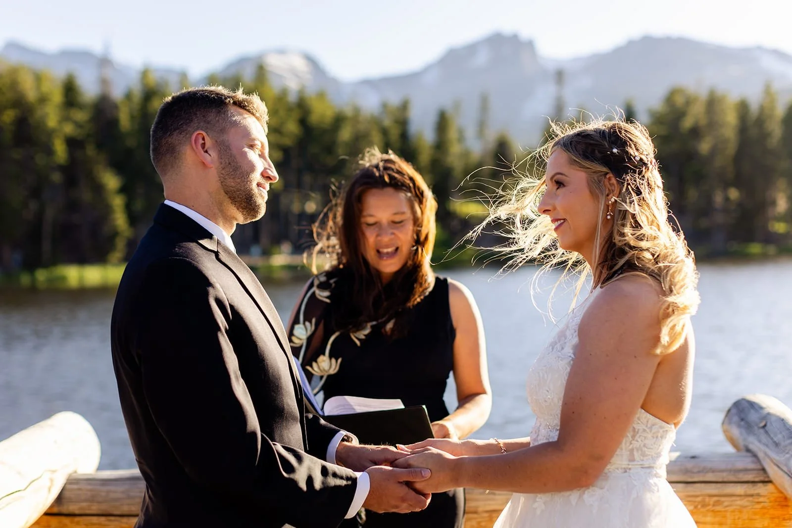 Officiant Lisa facilitates a ceremony on an alpine lake dock while the bride and groom look deeply into each other's eyes.