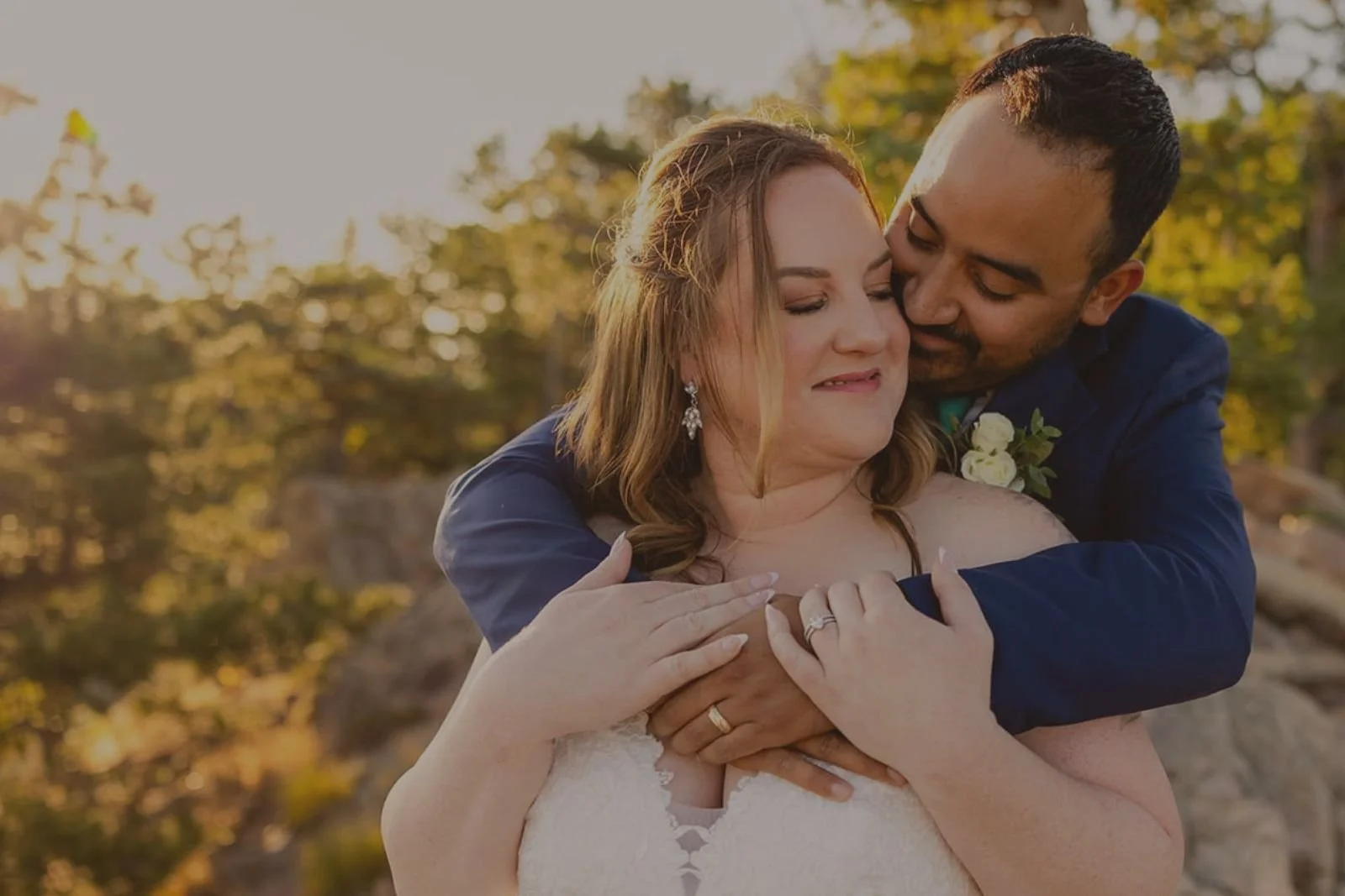 Closeup of a groom snuggling his bride in sunset light just before their elopement ceremony.