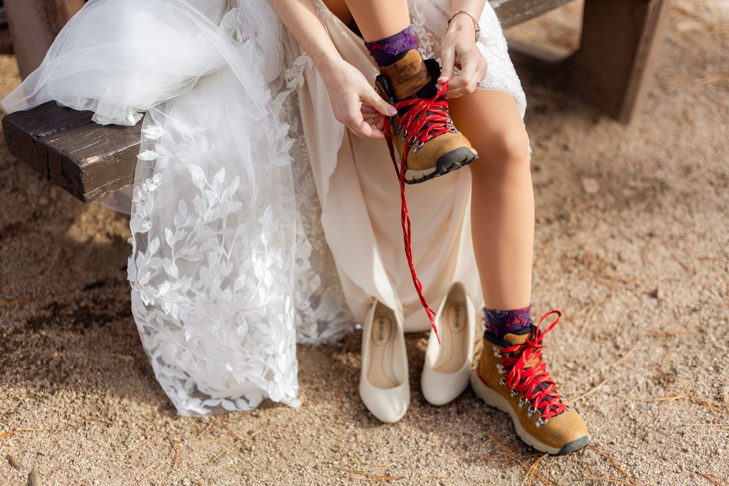 A bride changing out of her hiking boots and into dress shoes while on the trail.