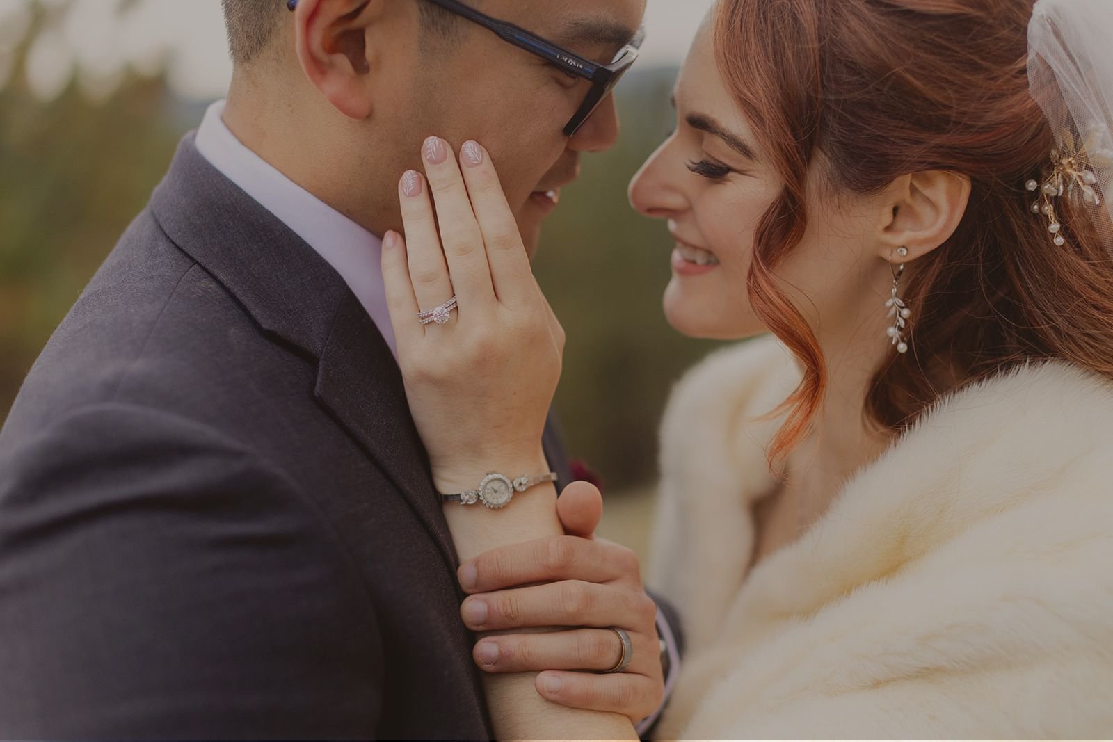 A newly-married eloping couple look into each other's eyes with the bride's hand lovingly on the groom's face.