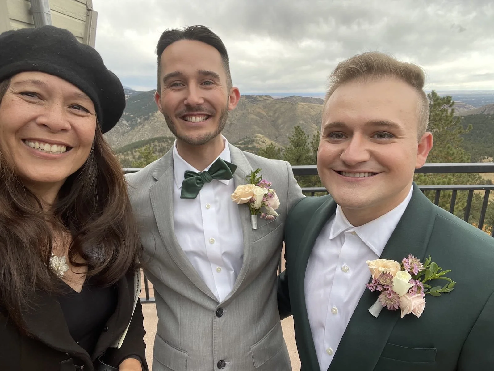 Officiant Lisa smiles with two grooms as she takes a selfie with them.