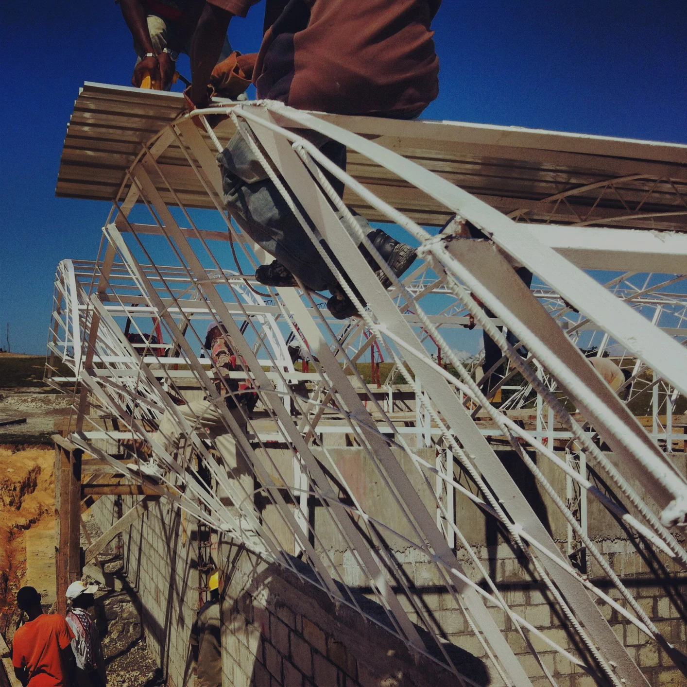  custom metal roof fabricated on site by local welders. &nbsp;The roof structure is designed to allow air to pass through the building to keep the interior cool while tall enough to allow&nbsp;the air calm where kids working don't want their paper bl