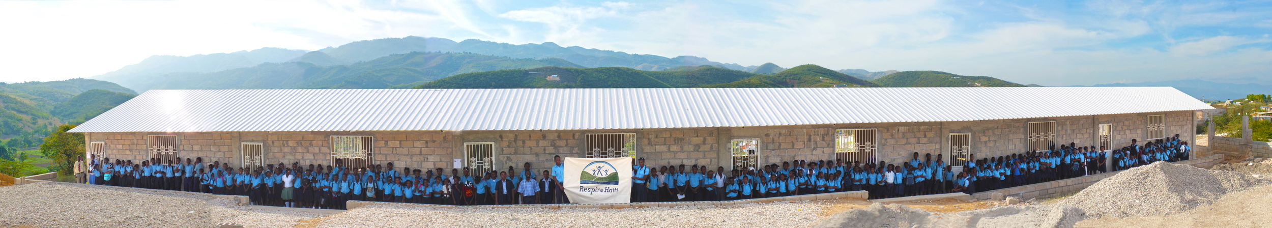 panoramic before finished plaster walls with all the kids in uniform before they have their first class inside of the first school building for the school. 