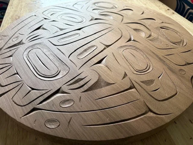 A side view of a Tlingit style carved circular panel.