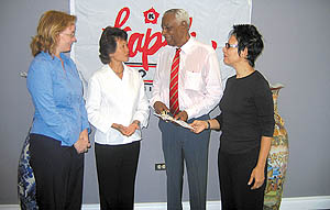 Diana Cohen-Chan, Kapok’s managing director, second from left, and Meiling, right, present a cheque to Justice Ulric Cross, director of the Cotton Tree Foundation, while administrator Patricia Gartland looks on.