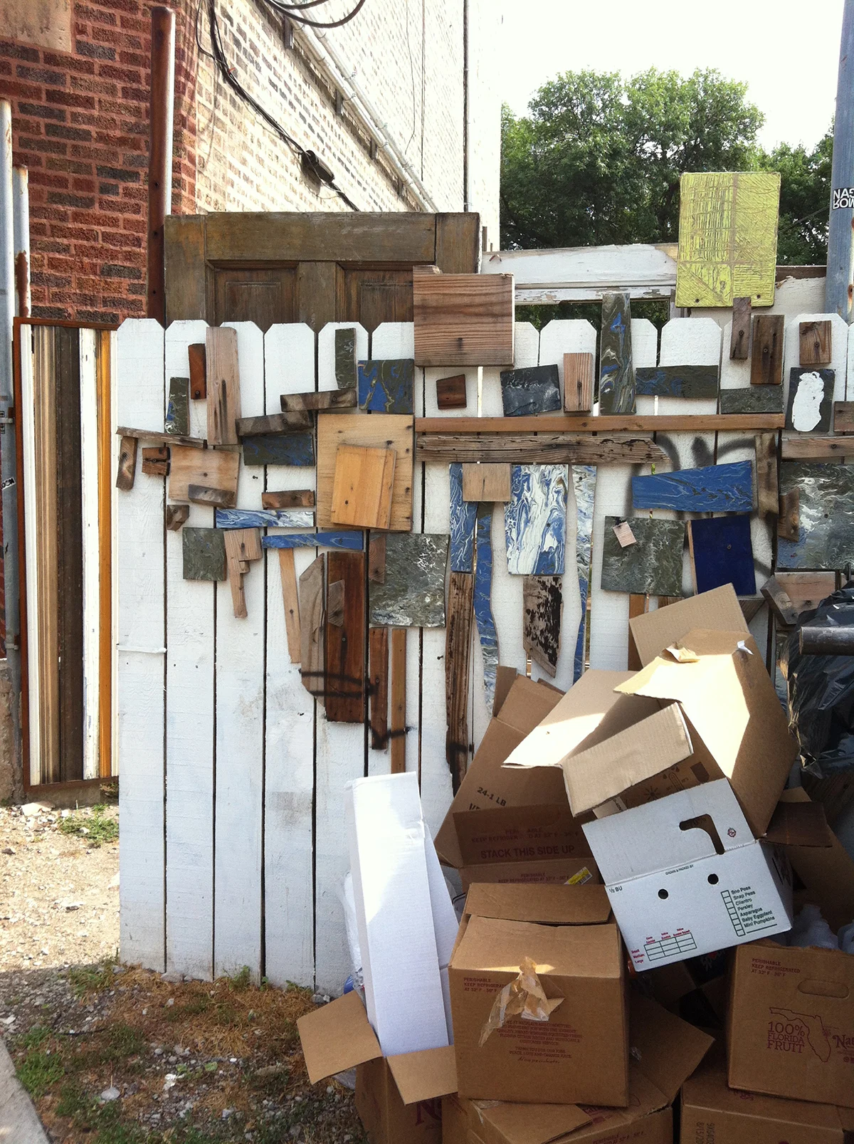     July 22:   I have been noticing these wood installations sprinkled around the city since I moved here. I spotted this one yesterday on a bike ride and had to spin around for a photograph. The linear fence and pile of boxes add to it’s geometric c