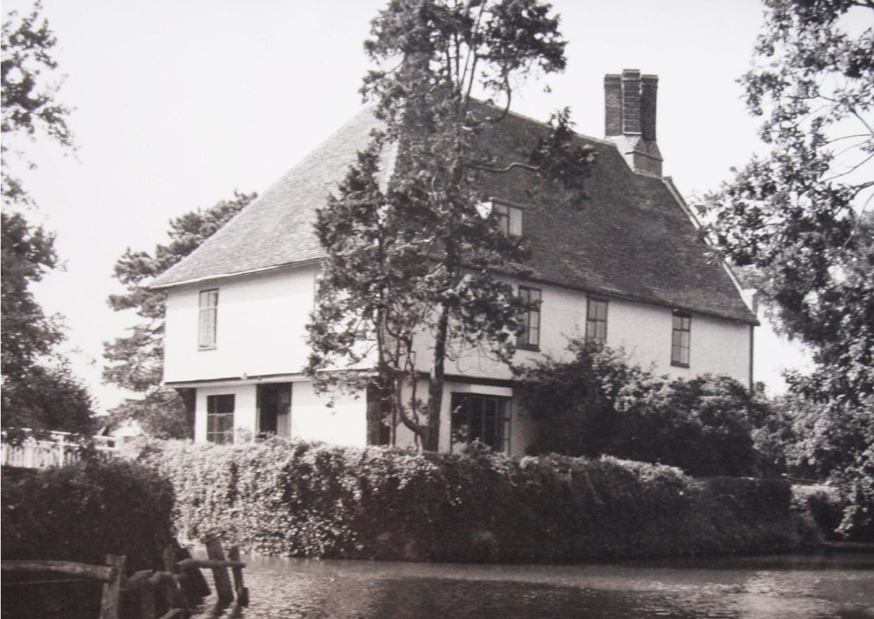 Fig.3 Letheringham Lodge (Eric Sandon Collection, SROI, K487/1/77) 2.26 Sandon then provides the following account of the building: The house occupies a moated site on the higher ground. Roughly in the centre of the moat is a structure in the form of a square. At each corner are massive oak posts. These corner posts are ornamented at about two-thirds of their height with triple arches surmounted by scalloped cresting, suggesting work of c.1460. The roof is hipped back to the central stack on the south side and this was probably repeated originally on the north side also, making a tall, regular-sided building with a pyramidal roof rising to a stack at the apex. The Jacobean work produced a brick gable end on the north side of the house, which descends sheer into the waters of the moat. 2.27 Sandon remarks that the purpose of the building remained obscure, adding that of the occupancy of the Lodge there seems to be no actual record until the early seventeenth century, and that there is a tradition that it was built as a hunting-lodge. 2.28 He concluded that: The structural evidence points to a building of the mid to late fifteenth century (possibly replacing one of an earlier date on an already moated site), to which a wing and staircase annexe was added in the early seventeenth century. The initials ‘EW’ and the date of ‘1610’ over the side entrance suggests that the extension of the house may have been built for Elizabeth Wingfield, the widow of Sir Thomas Wingfield who died in 1609. 2.29 In September 1991, Edward Martin and Timothy Easton led an excursion of the Suffolk Institute of Archaeology to Letheringham Lodge, with the ‘kind permission of Mr and Mrs M. R. Clough’. The account of the visit, which appeared in volume XXXVII.4 (1992) of the ‘Proceedings’ under the heading ‘Moats in the Landscape’, declared that this was: Very probably the smallest occupied moat in Suffolk. The earliest part is an extraordinary structure, originally square and jettied on all four sides, with large carved posts at the corners. 2.30 On the question of its original purpose, it was recorded in the account that it was sometimes claimed to be a hunting lodge, although it was noted that the structure does in fact lie outside the known park. However, it was put forward that: The hill- top location with extensive views suggests a ‘gloriette’, a lodge of seigneurial apartments set on a high point for contemplation of the scenery and for enjoyment of the healthy air. From time to time it may also have served as a vantage point for spectators of the hunt. 2.31 The review made reference to the early sixteenth century panelling, ‘removed c.1920’, and that heraldic evidence linked it with Sir Anthony Wingfield (born before 1488; died 1552) of nearby Letheringham Hall, the Lodge having formed part of the Hall estate down to twentieth century. 2.32 Wingfield served in the French campaign with distinction, being knighted in September 1513 following the capture of Tournai, and both he and his wife were also present at the Field of Cloth of Gold in June 1520. 2.33 Sir Anthony was, from 1539, Vice-Chamberlain of the Household, Captain of the Guard and Privy Councillor to King Henry VIII, he was made a Knight of the Garter in 1541 and was later an executor of the king’s will. He continued to serve under King Edward VI and was Comptroller of the king’s household by 1550. 2.34 I n May 1994, the ‘Moated site at Letheringham Lodge’ was scheduled under the Ancient Monuments and Archaeological Areas Act 1979 (as amended) for the reason that it is of unusual type, adding that in location, form and function it contrasts with the moated manorial site of Letheringham Hall which lies 1km to the north east, and that this contrast between the two sites, which are connected historically, is of particular interest in the study of land holding and land use in the area during the medieval and early post-medieval periods, particularly in relation to the Wingfield family. 2.35 The accompanying details describe Letheringham Lodge as being dated to the late fifteenth or early sixteenth century, with an early seventeenth century extension. They add that the earlier part of the structure is square and centrally positioned, and that the initials ‘EW’, carved with the date ‘1610’ above the entrance to the later wing, are thought to refer to Elizabeth Wingfield, widow of Sir Thomas Wingfield. The details also state that the Lodge has been identified as a place of resort for the enjoyment of the scenery and healthy air, away from the damp, riverside situation of Letheringham Hall. The house itself is excluded from the scheduling. 2.36 The Suffolk Historic Environment Record has the following entry for the scheduled ancient monument known as ‘Moated site at Letheringham Lodge’ (HER reference number LRM 003): Small, square moat, wet with sides 48yds long. The main approach to the site is across a brick and timber bridge in the middle of the S side. There is another timber bridge in the middle of the W side. The edges of the island are brick revetted (eighteenth or nineteenth century). Most of the island is covered by the house. The front part of the house was originally a square timber-framed structure, jettied on all sides. At each corner there are large wooden posts (two of these are now inside the existing house) decorated with a frieze of three arches on each of the exterior faces. Dated late fifteenth century by Pevsner and circa 1460 by Sandon. These posts support dragon beams which are in turn carried by a central brick chimney. On the N side is a timber and brick extension, including a tall brick gable wall which runs down to the moat. A doorway into this extension, on the W side, has `EW 1610' on the lintel. On the W side of the square structure there is a small wing containing a Jacobean staircase. The square structure does not, in origin, seem to have been a normal domestic building. One possibility is that it was a hunting lodge. However, it lies outside the known area of the deer park at Letheringham (in the SW corner of the parish). This was disparked in 1712. Nonetheless a park is clearly shown surrounding the `Lodge' on Bowen's map of 1755. The initials ‘EW’ over the door could stand for Elizabeth Wingfield. Elizabeth Drury married Sir Thomas Wingfield of Letheringham Hall in 1601. He died in January 1610, leaving Elizabeth as a young widow. She remarried in August 1610, to Henry Reynolds, but the marriage was a disastrous one and she and her husband were disputing in the courts by 1615. She died in 1620. Letheringham Lodge may have been built as a dower house for her, but it is doubtful whether a dower house would have been needed in 1610 as her son was then only a small boy. It is also odd that the date and initials are over a side door and not the main one. The unusually small size of the moat and the close correspondence between it and the size of the building makes it likely that the two are contemporary. It is possible that the site had a specialised usage, such as a banqueting house. This site survives well and is of unusual type. It contrasts well with Letheringham Hall, and is of interest in the study of land holding and land use in relation to the Wingfield family. 