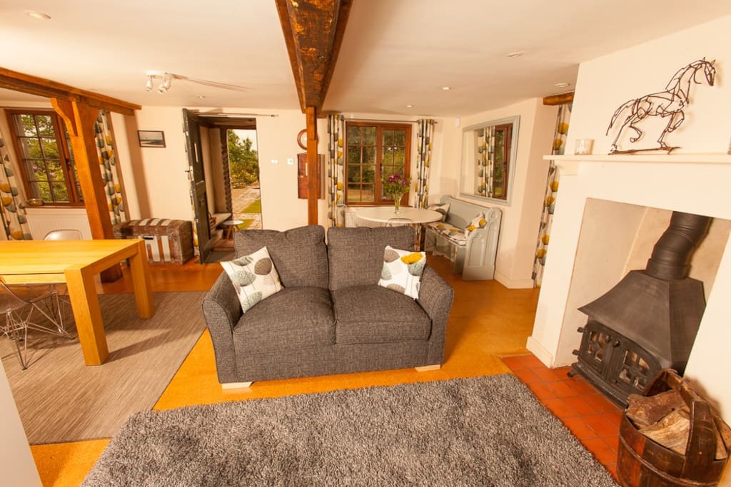 Sofa which is also a sofa bed. Woodburner and dining area behind