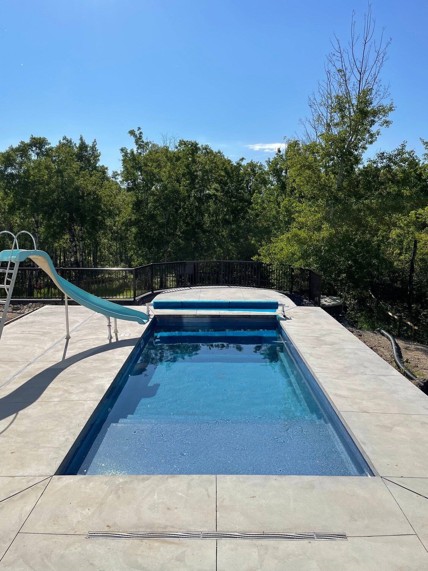 Which way would you enter: a cannonball? Hit the waterslide? A casual stroll down the steps? 🏊&zwj;♂️
.
.
.
#KeystoneOutdoorLiving #Saskatoon #LandscapeDesign #SwimmingPools #Patios #Decks #OutdoorLiving #Driveways #SaskatoonBackyards