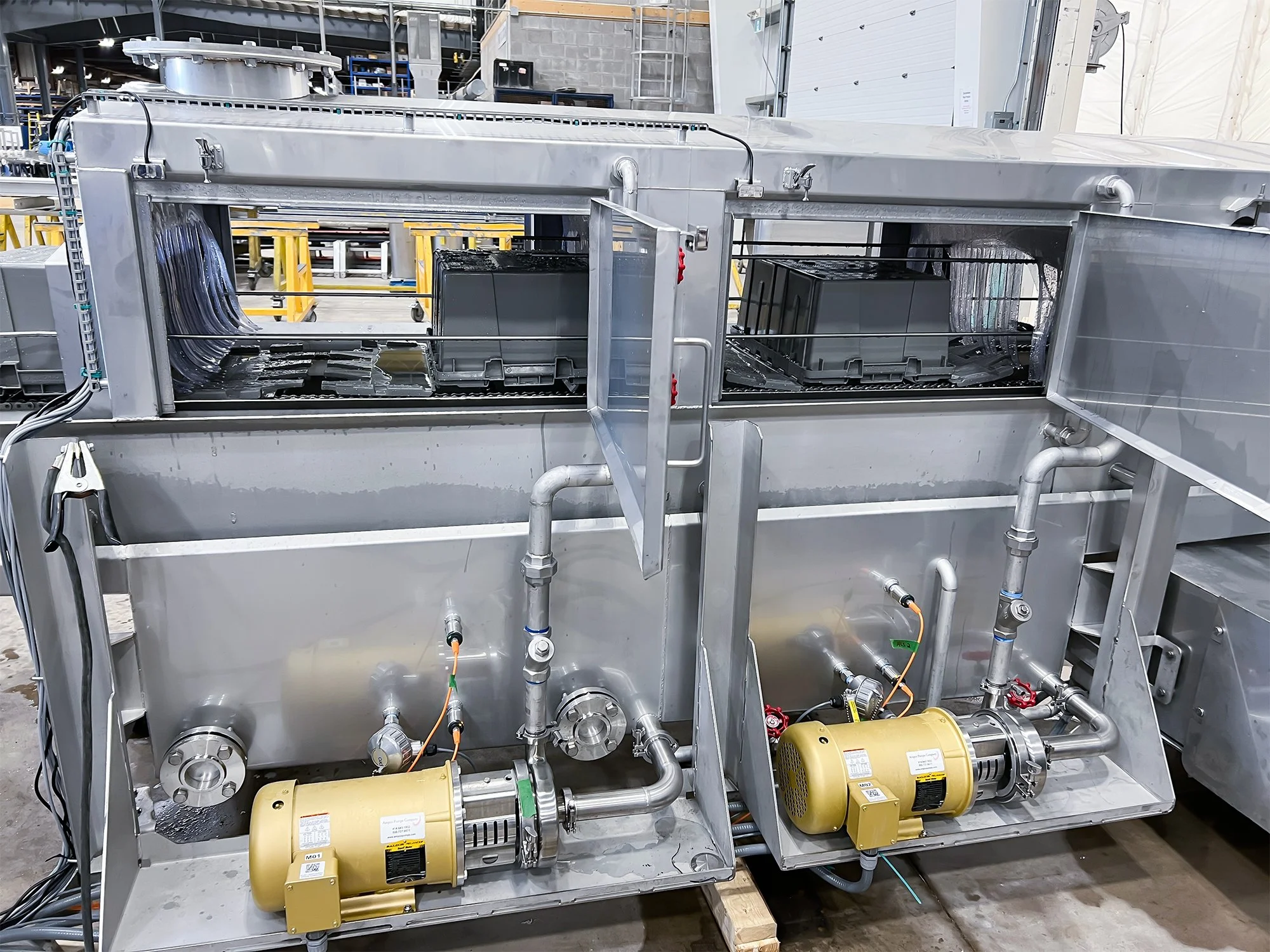 Pan washer with pipes, valves, and motors in a factory setting washing strawberries.
