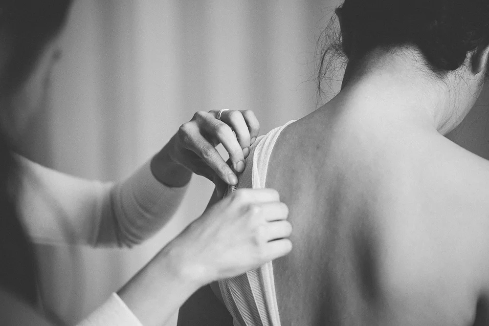 Sister helps bride adjust her dress at The Ivy.