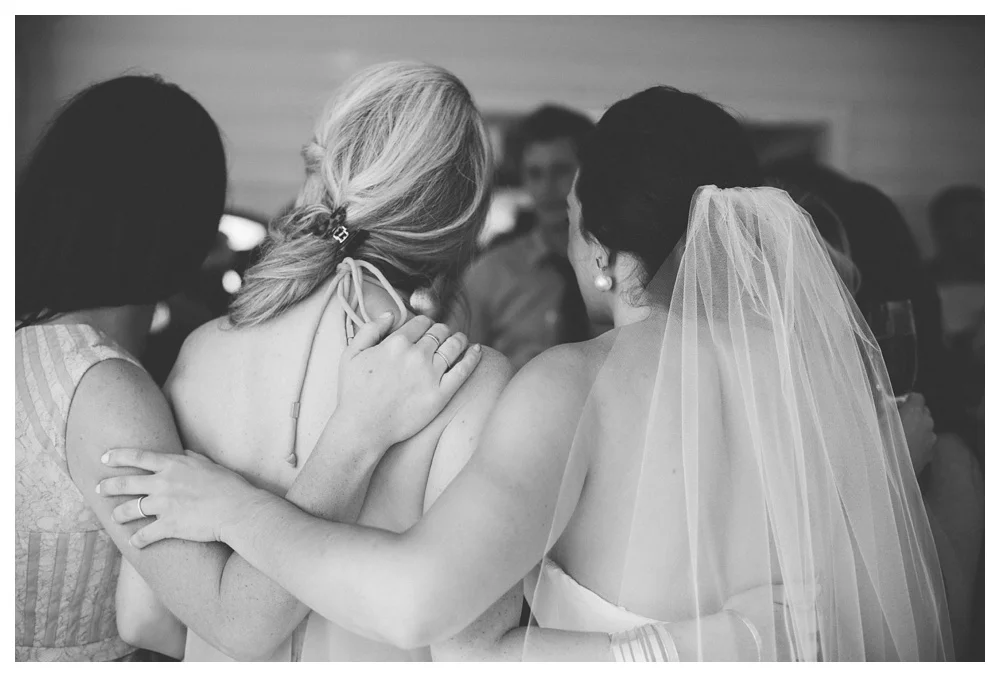 Friends hug at a rainy wedding at The Briars.