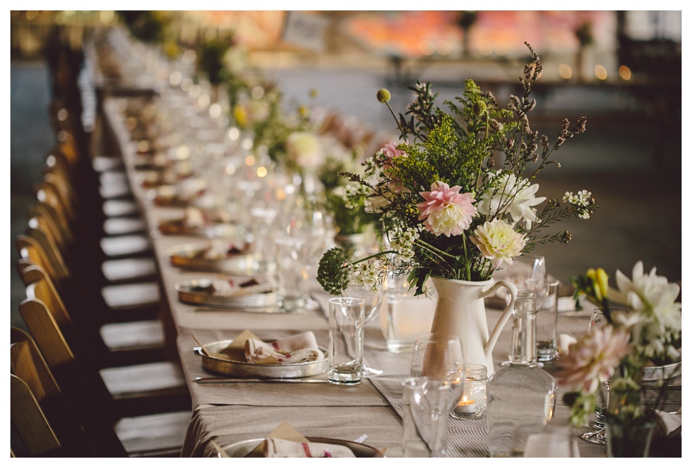 Natural, wildflower centrepieces at long, shared tables at Brickworks for a wedding.