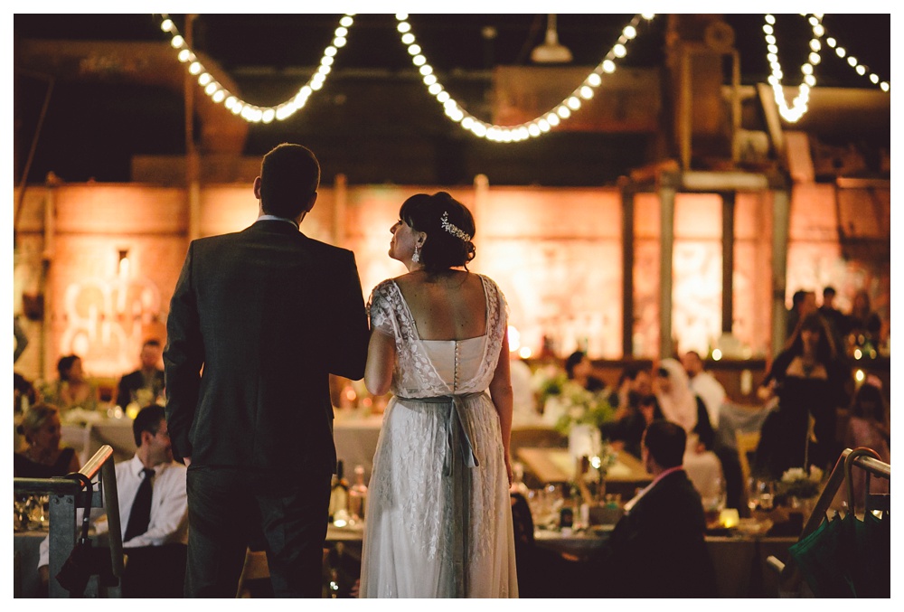 Speeches at a Brickworks wedding with string lights as decoration.
