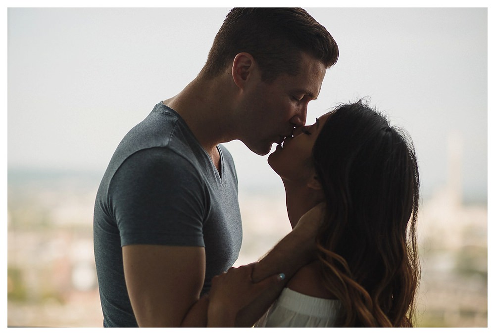 He leans over and kisses her bride to be on their engagement day. 