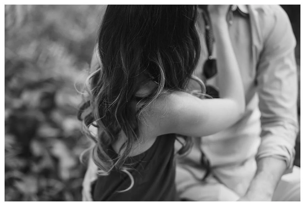 The bride's beautiful hair embraces her shoulders while she embraces her groom for their engagement photos. 