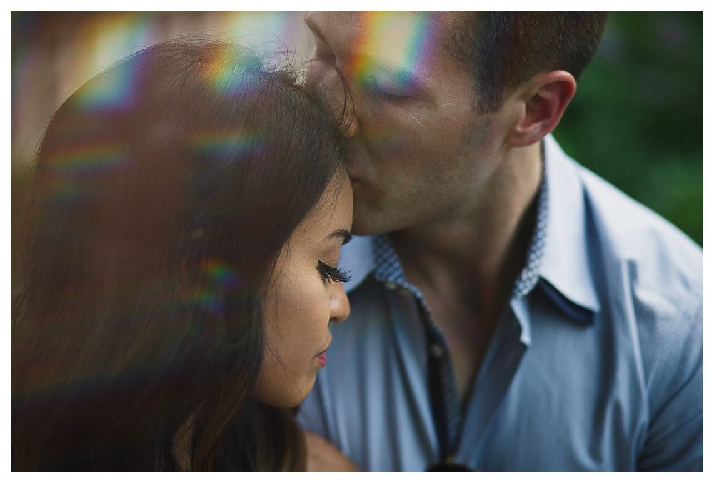 As the sun streaks through the sky, the bride and groom kiss on their engagement photo day 