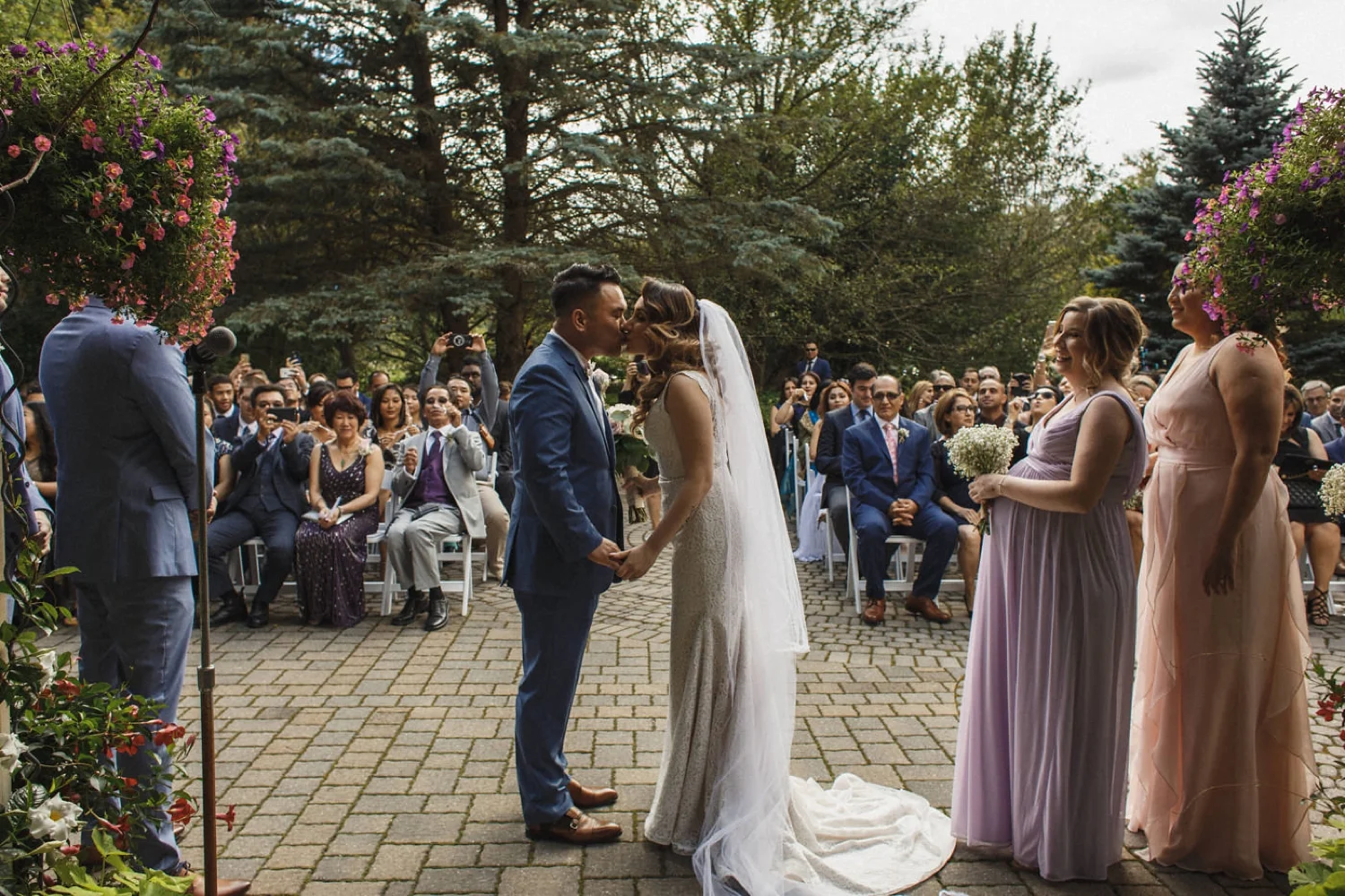 Couple kiss during outdoor ceremony in garden.