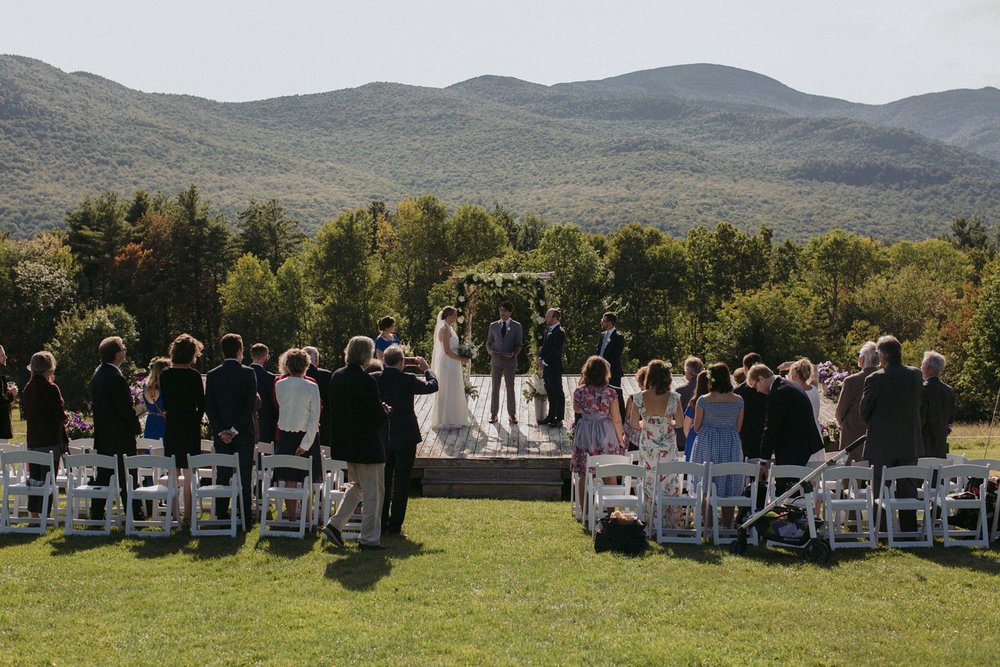 Ceremony in meadow under Vermont hills for destination wedding.