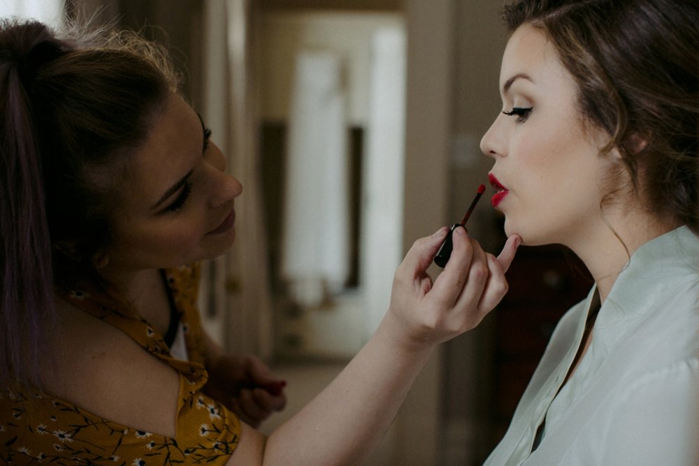 Bride putting on red lipstick at Langdon Hall wedding.