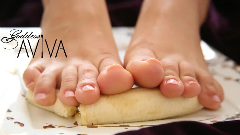 A woman's bare feet with pink pedicure is squishing a banana underneath for food play