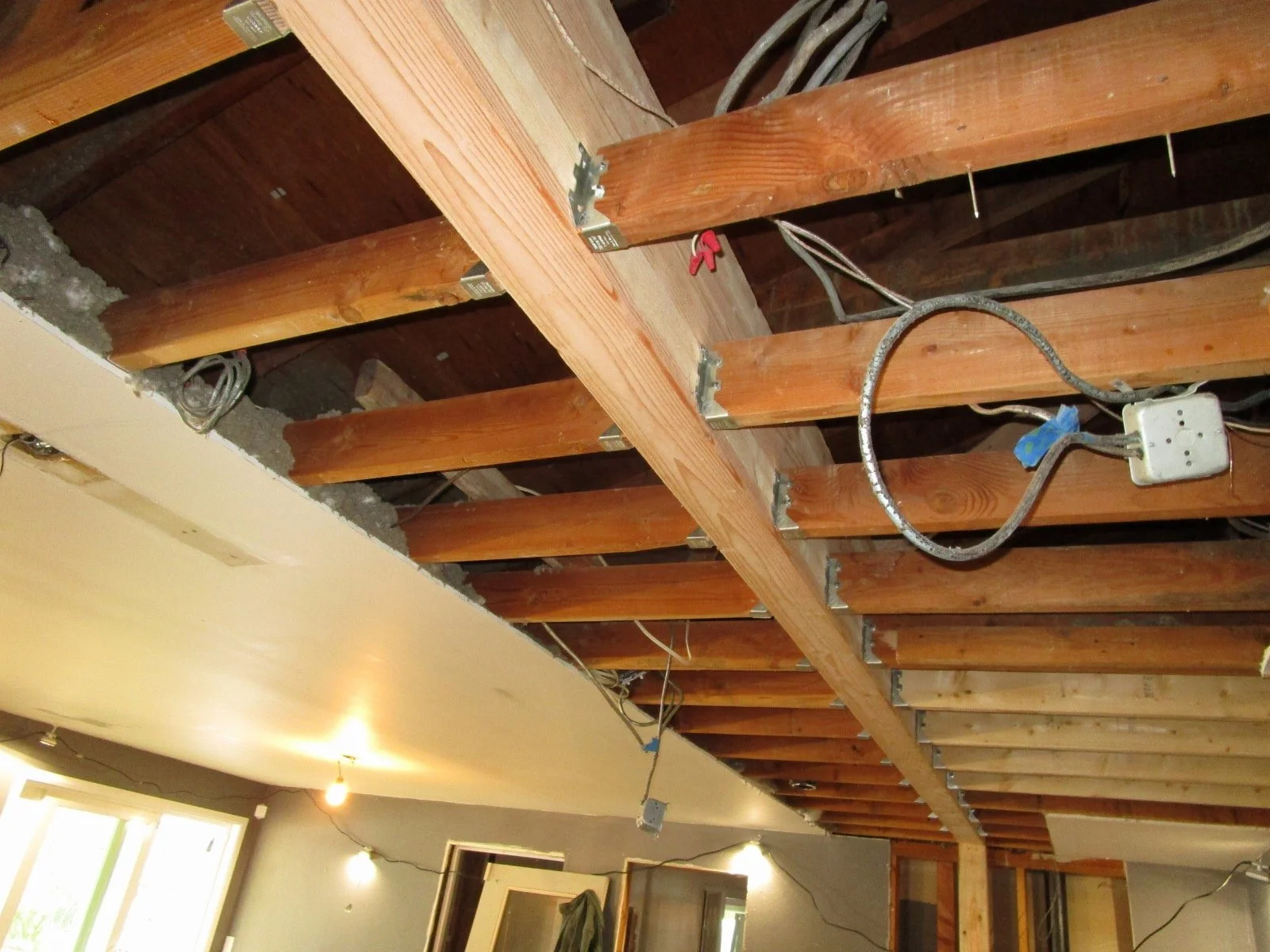 Up close of the existing ceiling joists hanging from the new glu lam beam. Beam also support the roof rafters.