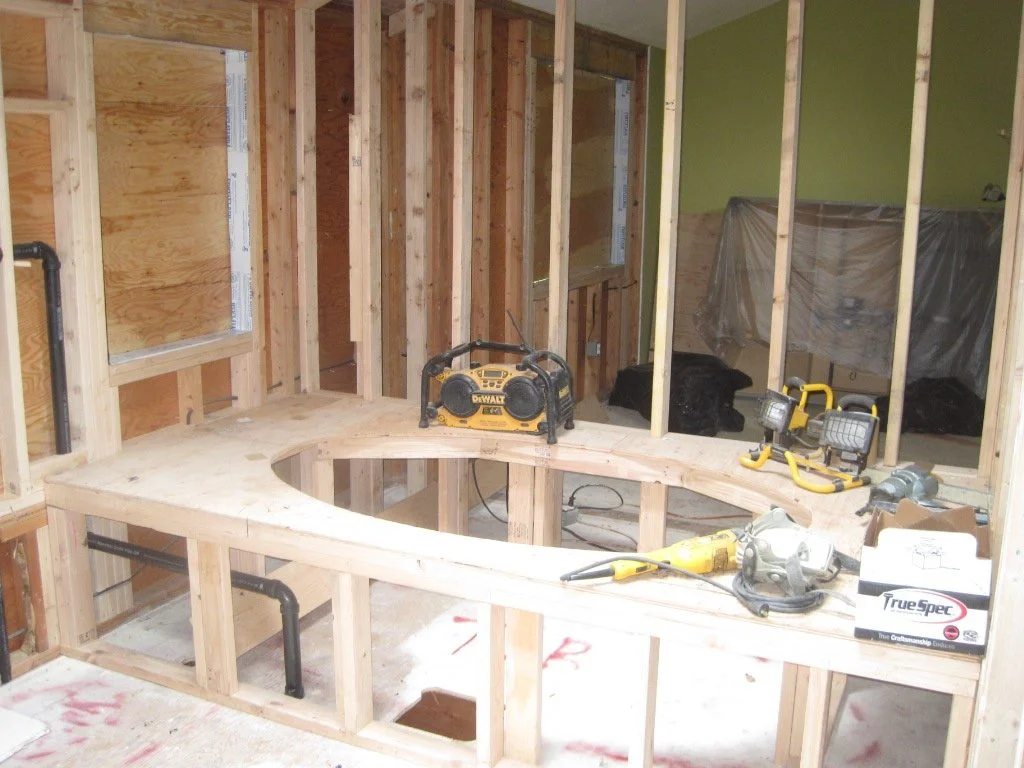 Work is progressing. Big platform for a big soaking tub, new window opening framed in on the left.