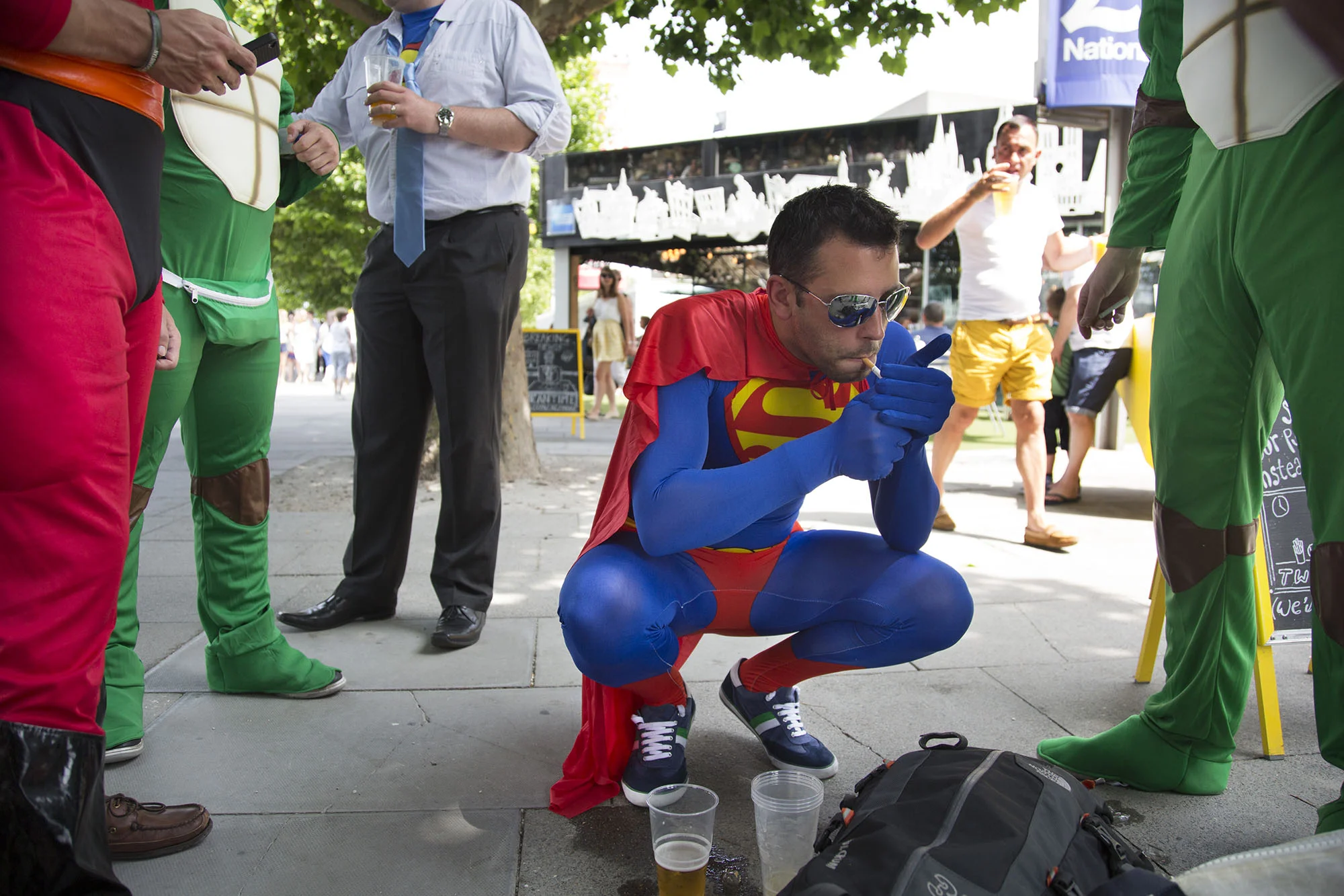 Superman lights up a cigarette near his stag party friends, who are dressed up in superhero costumes.