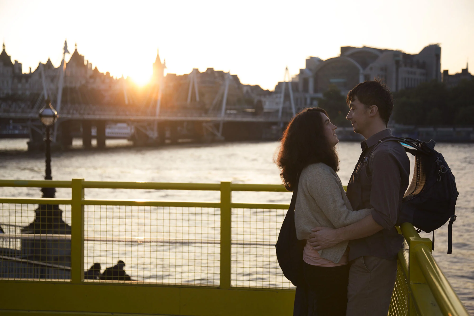 Lovers embrace at sunset on the yellow gantry beside the Royal Festival Hall terrace.