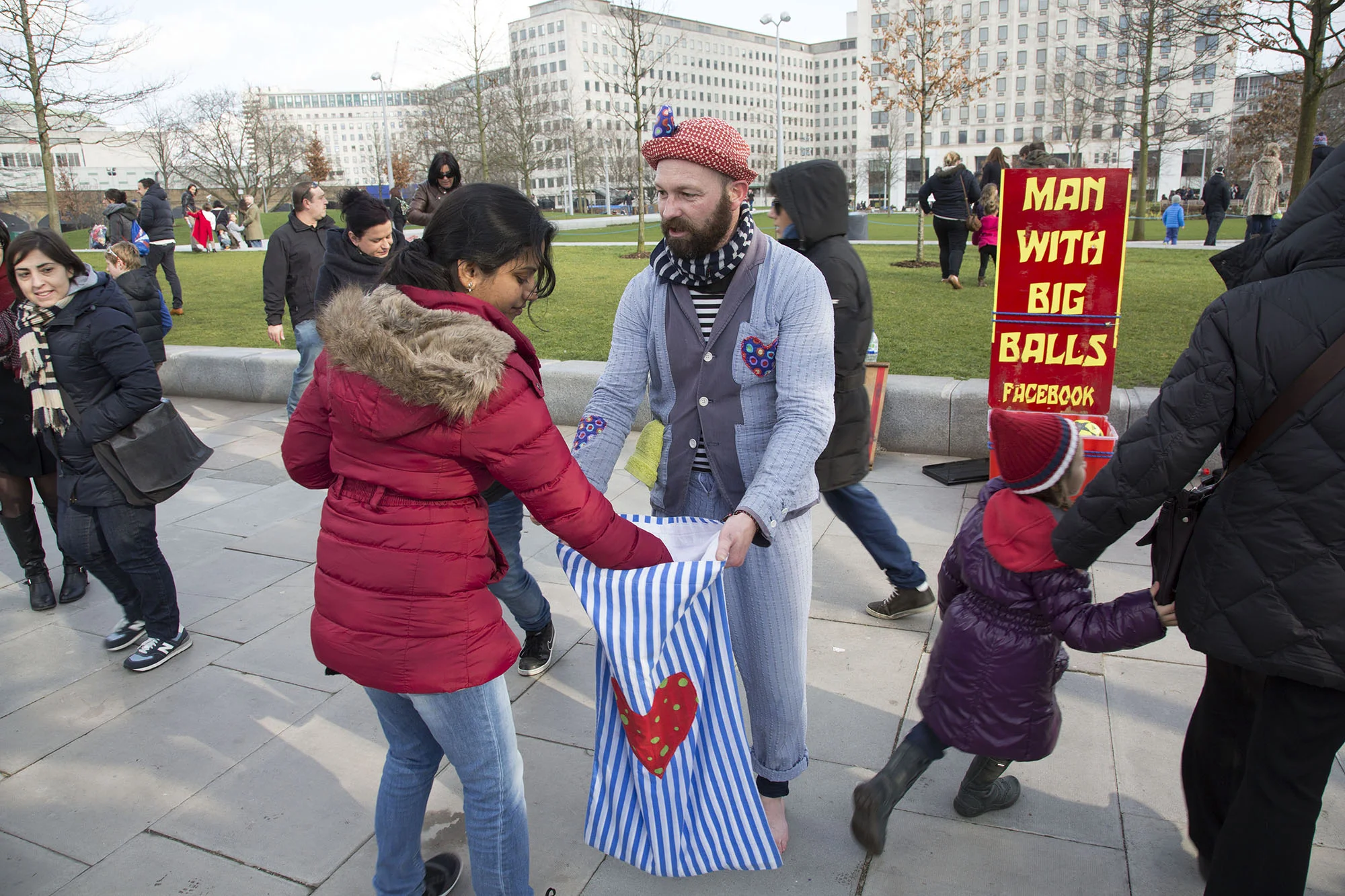 Man with Big Balls street entertainer gathers money from his audience after performing.