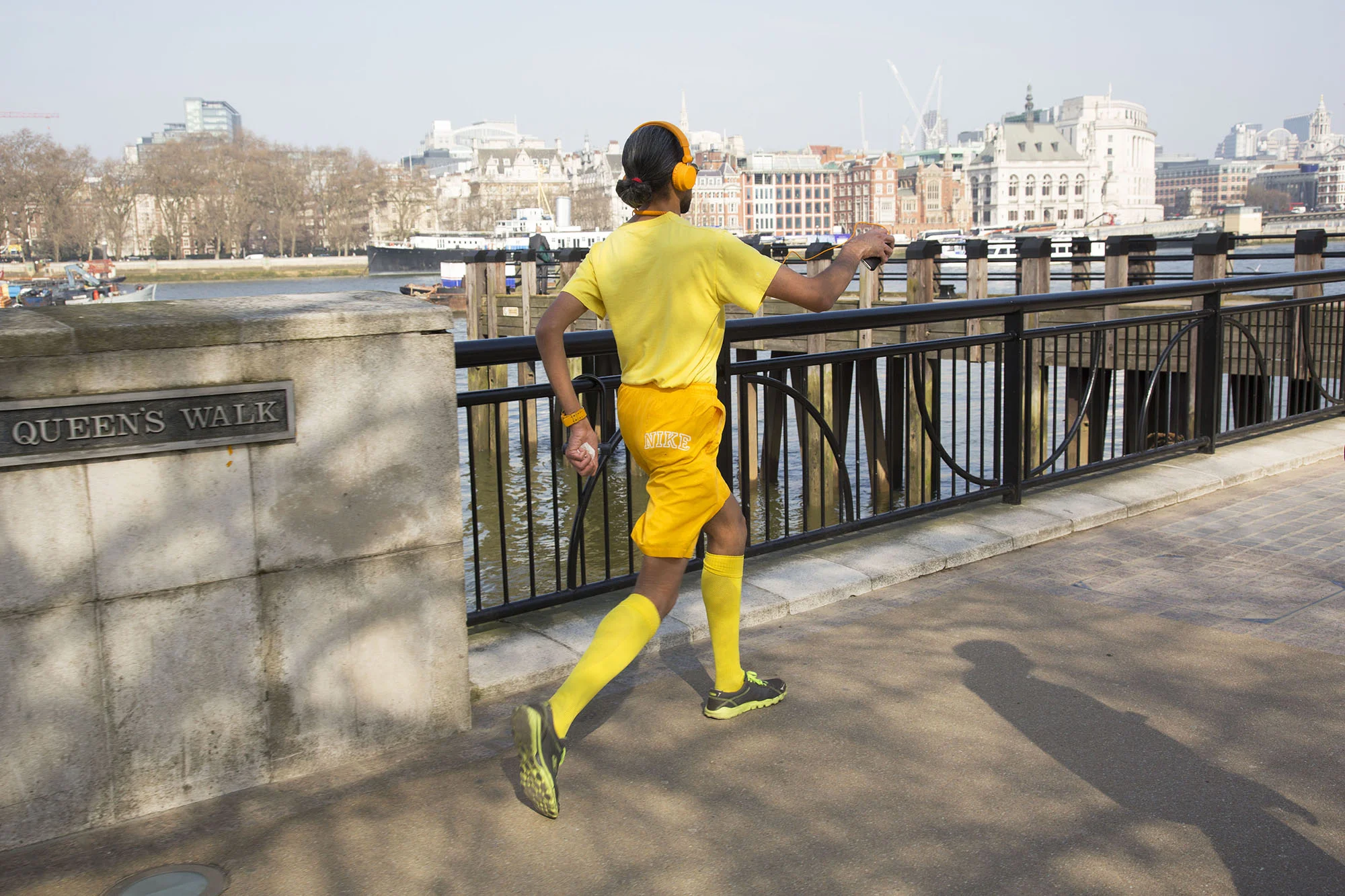 Man dressed in yellow, power walking along the Southbank at Queens Walk.